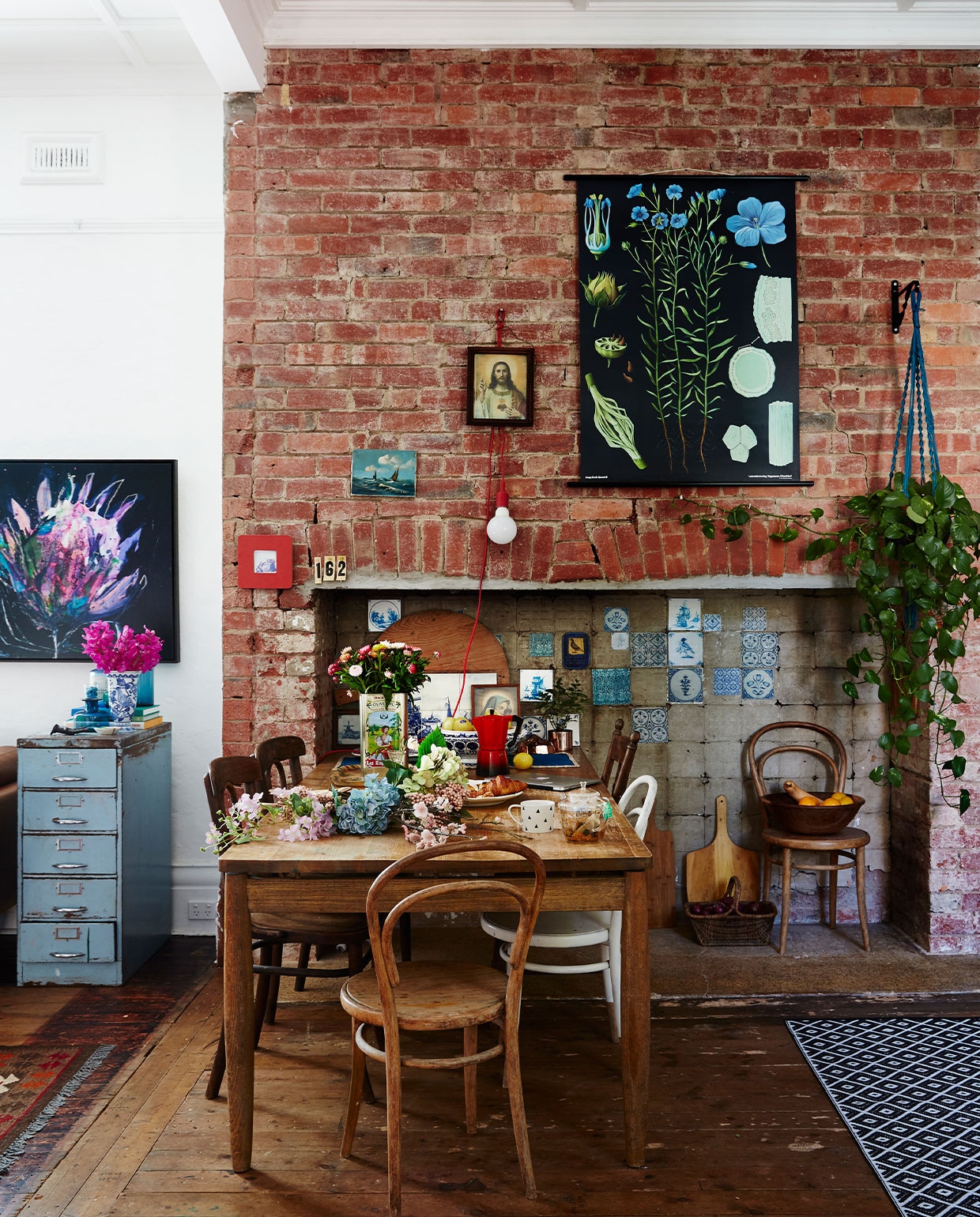 Hangplant en zwarte biologieposter Casa Verde Flowers. Delftsblauwe tegels, meubels, decoraties en accessoires vintage. Lamp Kikkerland. vtwonen 06-2022 | productie Living inside | styling Julia Green | fotografie Armelle Habib