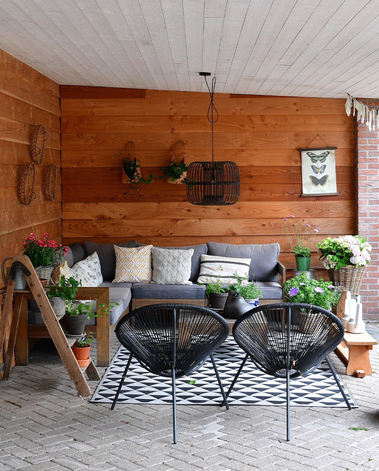 De veranda van ’t Heide Huisje is uitgevoerd in Douglas-hout. Een oude keukentrap doet dienst als plantentafel. Loungeset en stoelen Karwei, lamp De Panhoeve, vloerkleed Ikea, dienbladen als wandversiering Kwantum, gymbank kringloopwinkel, overig onbekend. NEE | vtwonen TUIN special 5 | fotografie Sietske de Vries | tekst Monique van der Pauw