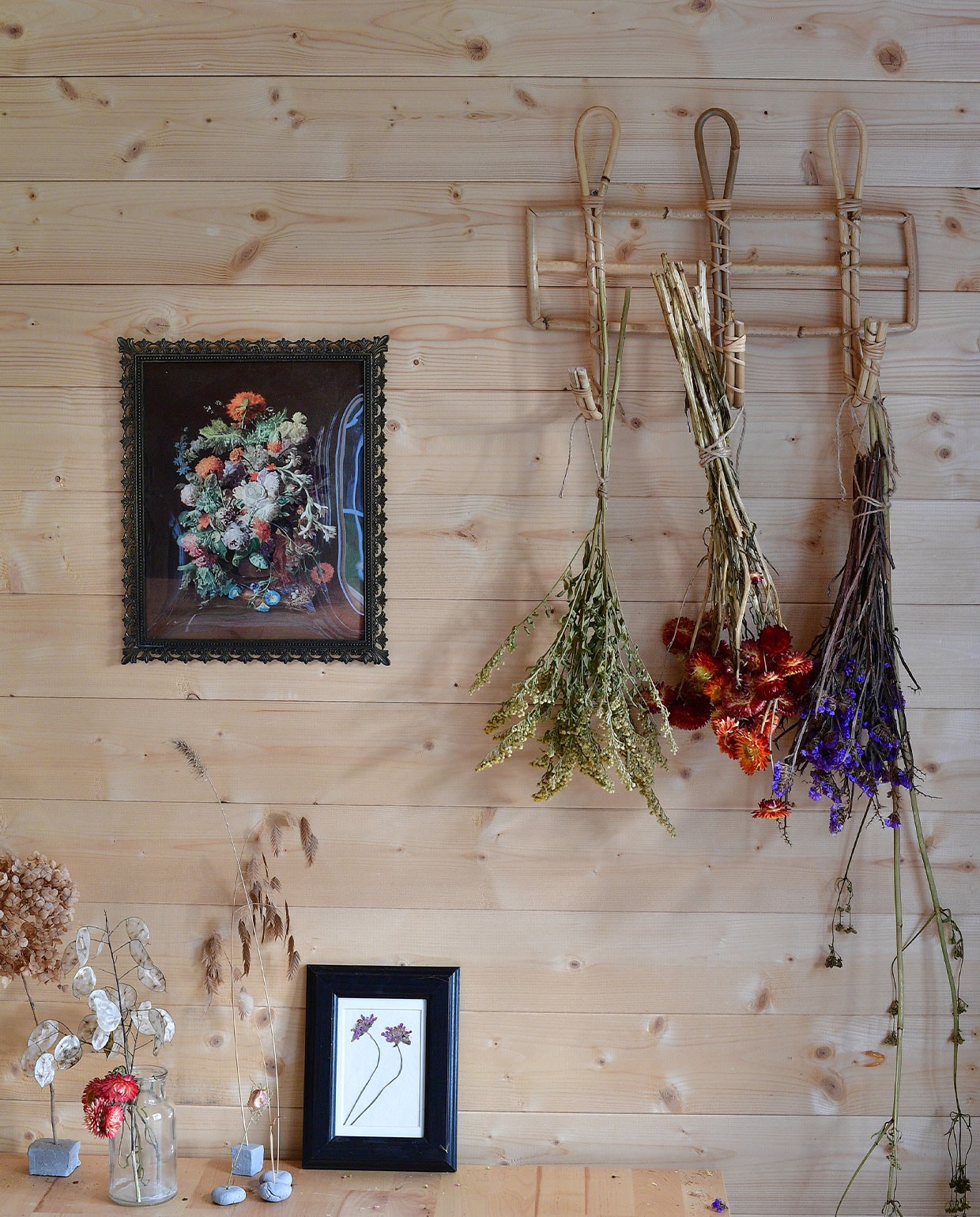 Aan een rieten kapstok van Dille &amp; Kamille hangen onder andere papierbloemen (midden) te drogen. Schilderij kringloop­winkel, gedroogde bloem in lijst zelf gedaan. NEE | vtwonen TUIN special 5 | fotografie Sietske de Vries | tekst Monique van der Pauw