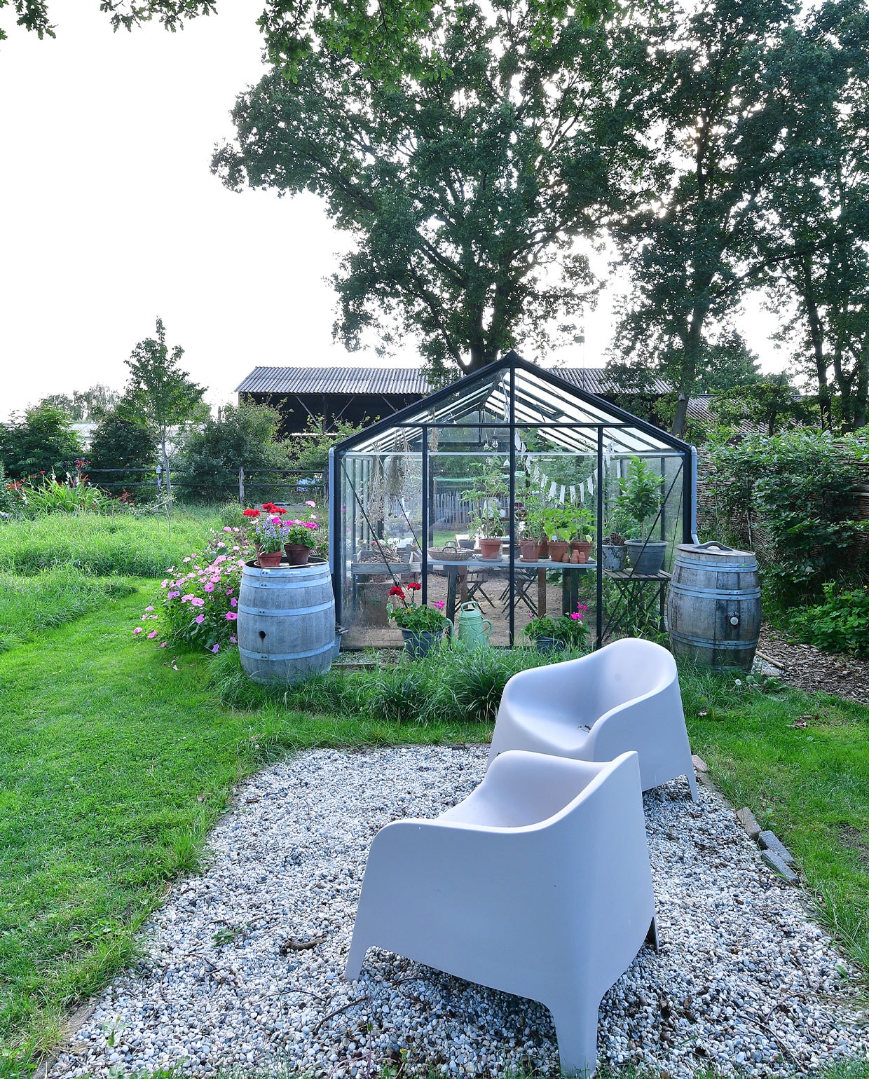Wijnvaten, gekocht bij een Nederlandse wijnboer die ze over had, kregen een nieuw leven als regen- en sierton. Links staan Lavatera’s en dahlia’s. Stoelen Ikea. NEE | vtwonen TUIN special 5 | fotografie Sietske de Vries | tekst Monique van der Pauw