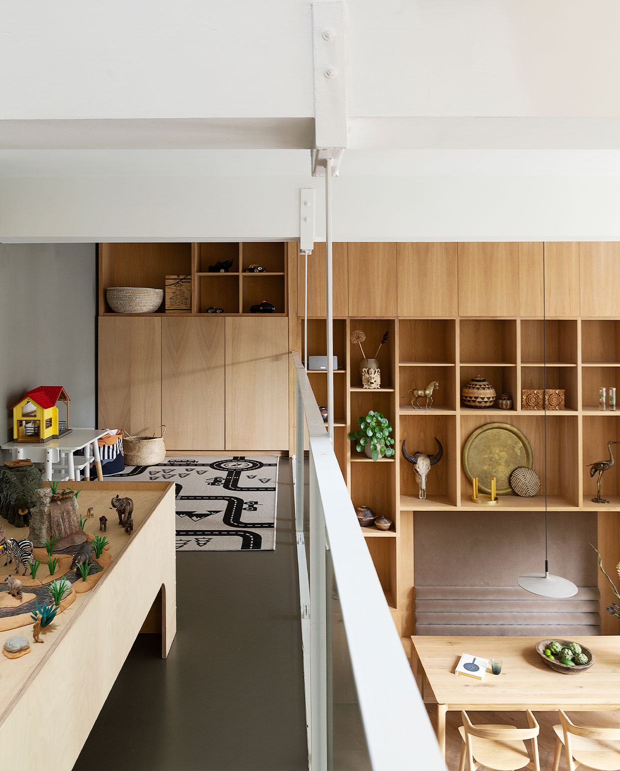 Eikenfineer wandkast eigen ontwerp in samenwerking met timmerman Thijs de Jong. Objecten van diverse reizen meegenomen. Speelkleed Wehkamp. Speeltafel gemaakt door Timmer Toko van Overdijk, speelgoeddieren en geel huisje Schleich. Witte tafel en kruk Playtive. Manden Ikea, ronde bak Return to Sender, hoge bak Kapla. Egalinevloer vtwonen 06-2022 | productie Martine Benjamins | styling Emmy van Dantzig | fotografie Jansje Klazinga