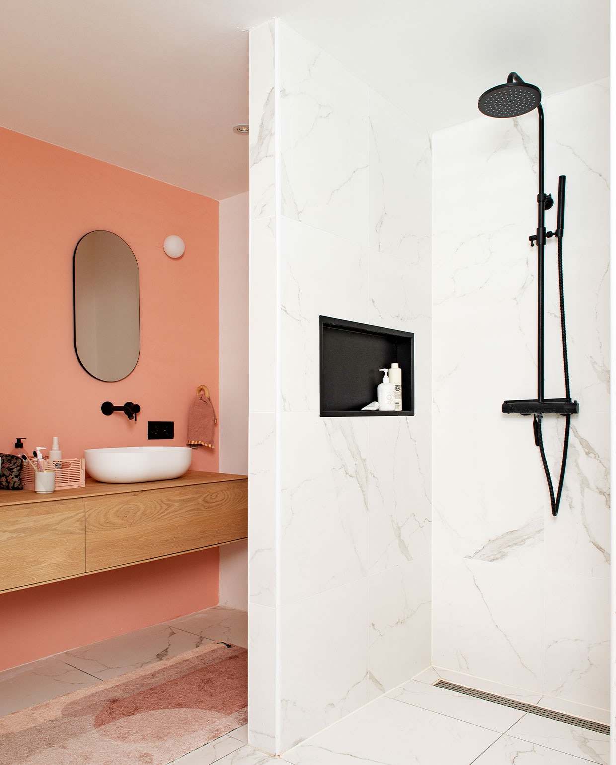 Muurverf Subtle Red van Flexa. Marmeren tegels Tegelmegashop. Wastafelmeubel en wasbak Houtmerk. Kranen en douchegarnituur Saqu. Spiegel House Doctor. Wandlamp Flos. Badmat Mad About Mats. vtwonen binnenkijken special 12-2021 | styling Jeske Weel | fotografie Caroline Coehorst