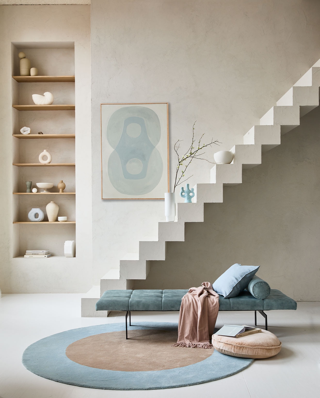 Op de muur kalkverf Fresco Old Flax van Pure &amp; Original, per liter € 55,- (paint-pure.nl). Daybed Alfies in Faded Blue, 190x70x38 cm (bxdxh) vanaf € 828,- (versmissen.nl). Schilderij Longing for, acryl op canvas van Anne Olde Kalter, 70×100 cm prijs op aanvraag (anneoldekalter.com). Rond vloerkleed Dot, 200 cm (Ø) € 699,- (festamsterdam.com). Rond fluwelen zitkussen van HKliving, 60 cm (Ø) € 55,99. Vaas Shell Pot van Ferm Living € 99,-, vaas Forma large van Bolia € 90,- (vtwonen.nl). Lichtblauwe kandelaar van &amp;Klevering € 35,- (groenenakker.nl). Witte kom op trap € 39,99 (zarahome.com). Vazen met bol erop op bovenste plank prijs op aanvraag (byjoa.nl). Witte vaas cirkel € 14,99 (hm.com). Vaas van 101CPH op tweede plank € 39,- (debijenkorf.nl). Schaal op voet € 59,95 (urbannatureculture.nl). Overig privébezit. JA | vtwonen 04-2022 | Styling Cleo Scheulderman | Fotografie Jeroen van der Spek | Assistentie Krystel-Jane Robinson, Jamaine Festen