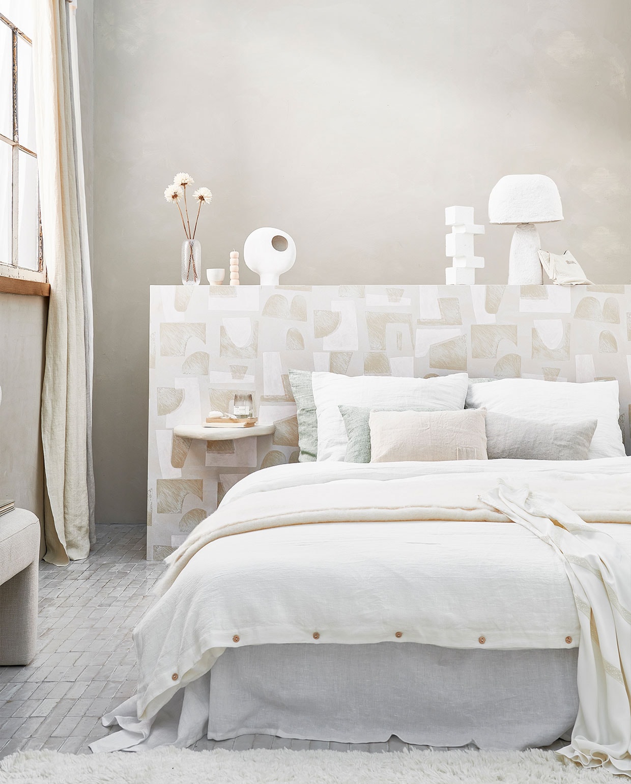 Muurverf in kleur Mallorca van We are Wowmakers, vanaf 2,5 liter € 110,- (fabriekzuidermeer.shop). Gestoffeerde bank van HKliving € 449,-, witte vaas van Be Pure Home € 45,30, vloerkleed van Linie Design € 715,-, wit blokornament van vtwonen € 35,25 (vtwonen.nl). Gordijnen gemaakt van linnen stof Brera Lino van Designers Guild, per meter € 86,- (wva.nl). Hoofdbord behangen met behang Tutto uit collectie Voiles de Papier van Elitis, per rol € 196,- (loggerewilpower.com). Pleisterwerk wandplank € 90,-, grijs linnen sierkussen € 56,- (velv.nl). Glazen vaas € 24,- (bolia.com). Mok € 14,90 (letoile.store). Handgemaakte kaars, set van drie € 45,-, toilettas € 60,-, zandkleurig kussen met vierkant vlak € 69,- (sukha.nl). Witte keramieken vaas € 44,95 (urbannatureculture.com). Witte papier-maché tafellamp € 129,- (hm.com). Linnen laken in kleur Pure White, vanaf € 129,-, linnen dekbedovertrek in kleur Warm White, vanaf € 155,-, linnen kussenslopen in kleur Warm White en Sage, vanaf € 30,- (bymolle.com). Overig privébezit. vtwonen 06-2022 | Styling Danielle Verheul | Fotografie Sjoerd Eickmans | Assistentie Sanne Ketelaar, Minke van Bakel