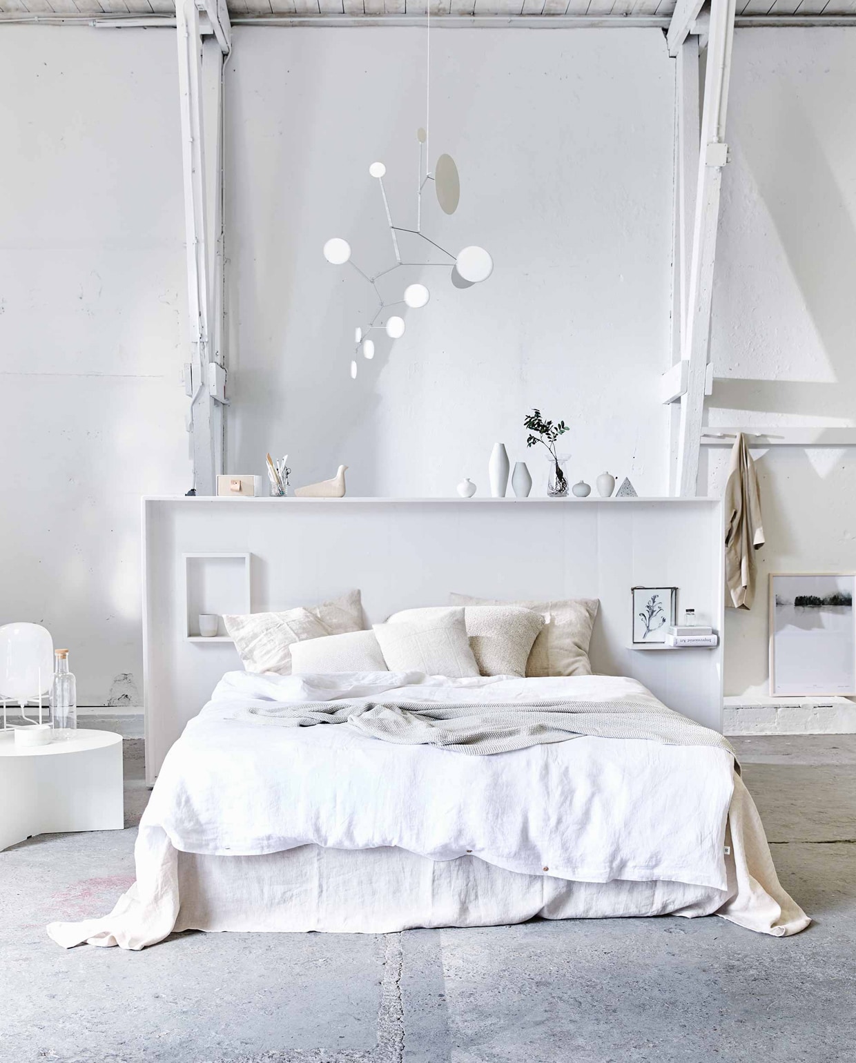 Hoofdbord (Combitex). Linnen laken Almond, linnen dekbedovertrek Pure white, kussenslopen Seashell, gerecyclede denim plaid in off white (By Mölle). Bijzettafel Slit Table XL White, fles met kurken dop (Hay Amsterdam). Lamp Pulpo small white (Mobilia). Kleine vaasjes (Maison NL). Hoge vazen van porselein (CK Ceramics). Piramide van steen (Restored). Glazen bollenvaas, linnen jas (Six and Sons). Afbeelding Calm Botanics in lijst (My Deer’s). Witte dot mobile (Lappalainen via Etsy). Lage schaal op tafel, beker in kast (Annemieke Boots Ceramics). Opbergdoos met nude laatje (&amp; Other Stories). Kussen van witte alpaca wol, groot kussen Colombia (Couleur Locale). Witte linnen kussenhoes (H&amp;M Home). Houten Eames vogel (Homestede). Tekening in lijst van Anke Loijens en overig privébezit. vtwonen 2017-07 | Fotografie Jeroen van der Spek | Styling Cleo Scheulderman