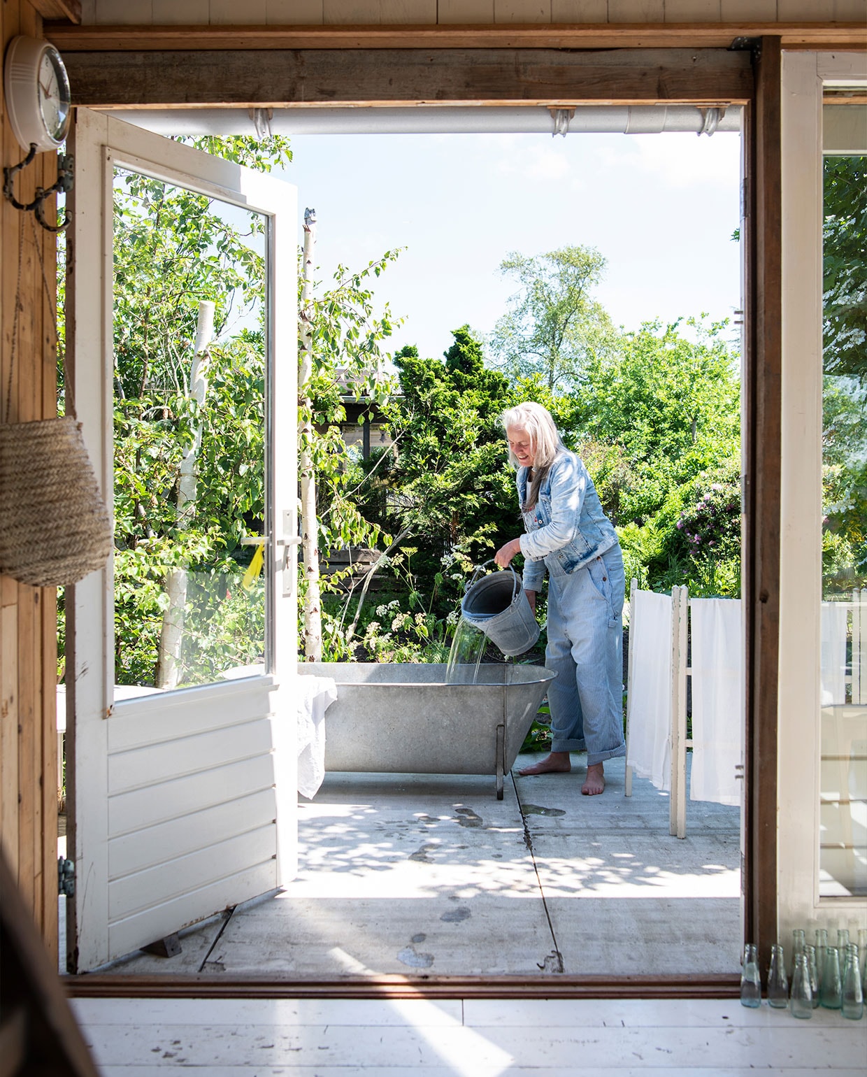 Simones favoriete plek in de tuin: het vintage zinken bad van Van Dijk &amp; Ko. Droogrek Dickens Style, mand aan muur Naturals by San, klok kofferbakverkoop Buitenhuis. vtwonen tuin special 5 | Productie Insidehomepage | Styling Myla Griese | Fotografie Louis Lemaire