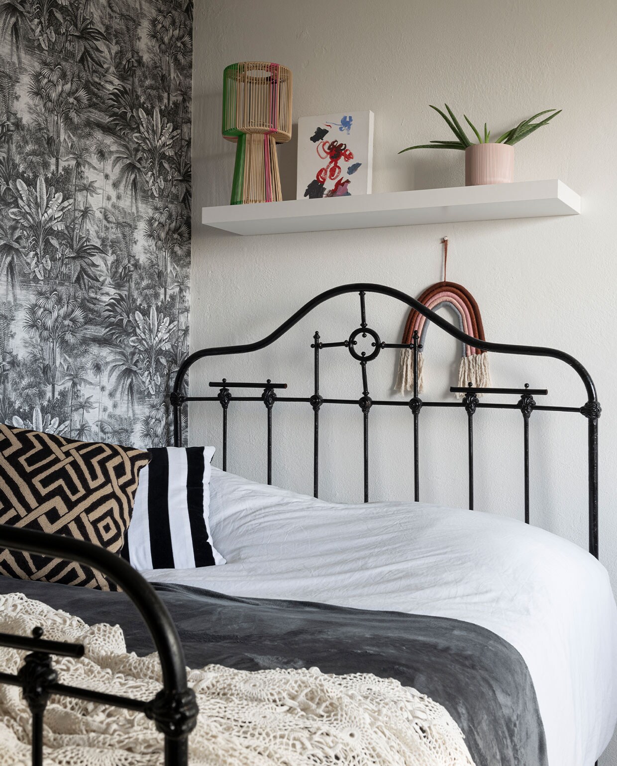 Behang en regenbooghanger Kwantum. Bed uit het ouderlijk huis van Noor. Gestreept kussen HKliving, geometrisch kussen Alaloes Object &amp; Interieur. Gehaakte sprei gemaakt door Noors oma. Draadlamp Kitsch Kitchen. vtwonen special binnenkijken 12-2021 | styling Sharon Roest | fotografie Caroline Martinot