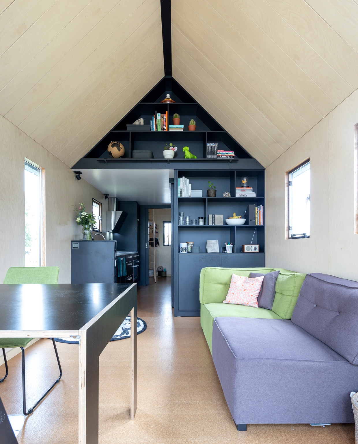 Onder de kurkvloer ligt elektrische vloerverwarming. De wanden, vloer en plafond zijn aan de binnenkant bekleed met panelen van houtfineer. De hoge zwarte kast, een ontwerp van Menno en Rhona, maakt slim gebruik van de ruimte in de nok. Achter de kast bevinden zich de keuken, de badkamer met opslagruimte en Viks slaapkamer. vtwonen special tiny houses | fotografie Henny van Belkom | tekst Jack Meijers