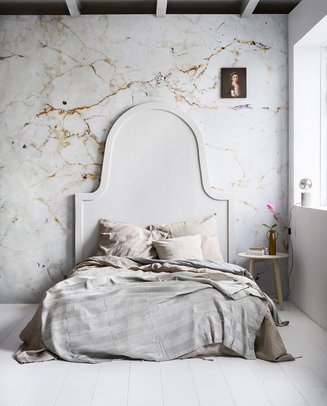 Fotobehang Milano met marmerprint, 300×300 cm per rol (karwei.nl). Bed-achterwand, 200×160 cm (com-anders.nl). Grijs-blauw plaid Vägmallä, lichtbruin bedlinnen Puderviva, 240×220/60×70 cm, bijzettafels Kragsta, 51×49 cm (hxØ) en 45×35 cm (hxØ) set van 2 (ikea.nl). Grijs flanellen bedlinnen, hoeslaken Hotel (hema.nl). Vaas van Bloomingville (vtwonen.nl). Tafellamp Charis (kwantum.nl). Canvas Miss Susanna Gardiner, 25×30 cm (werkaandemuur.nl). Overig privébezit. vtwonen 03-2020 | styling Marianne Luning | fotografie Stan Koolen
