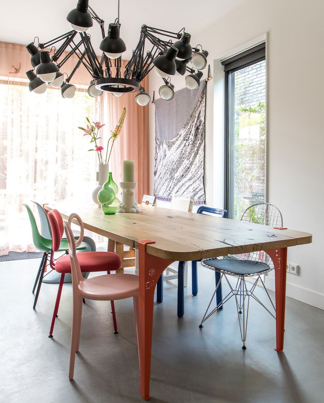 Lamp Dear Ingo van Moooi, eettafel eigen ontwerp by Maykel. Stoelen van linksvoor naar achter Qeeboo, Maarten Baas, Vitra, van rechtsachter naar voor Piet Hein Eek, Studio Job, Dirk Vander Kooij, Vitra. Witte vaas HKliving, bottle vaas Klaas Kuiken, witte kandelaar Jorine Oosterhoff via Cor Unum, wandkleed Plaid Skinn Throw No2 van Roos Soetekouw. Overgordijnen op maat gemaakt door stoffeerder, vitrage van Kvadrat-stof, kleur op muur onbekend. vtwonen 2-2022 | styling Kim de Groot | fotografie Anke Leunissen | tekst Mirjam Rosema-Verhulst