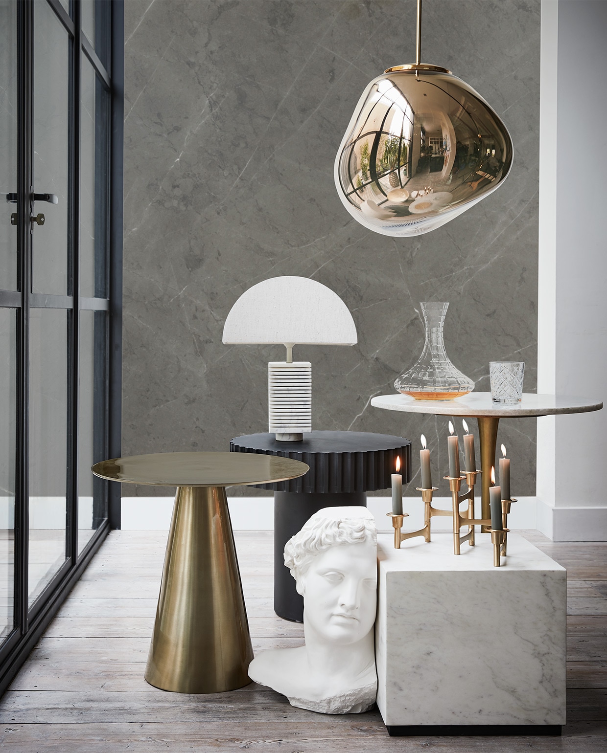 Messing tafel 45×49 cm, zwarte tafel, witte marmeren tafel gipsen beeld Apollo, tafellamp (hkliving.nl). Hanglamp Tom Dixon van Loods 5 Design (loods5.nl). Kandelaar (vtwonen.nl). Karaf (polspotten.nl). Glas Frasera (ikea.nl). De achterwand is behangen met een custom made behangpaneel met daarop een uitvergrote afbeelding van wandtegel Classic Antracite Mat van vtwonen (vtwonen.nl/vtwonen-collectie). vtwonen 13-2019 | styling Fietje Bruijn | fotografie Alexander van Berge