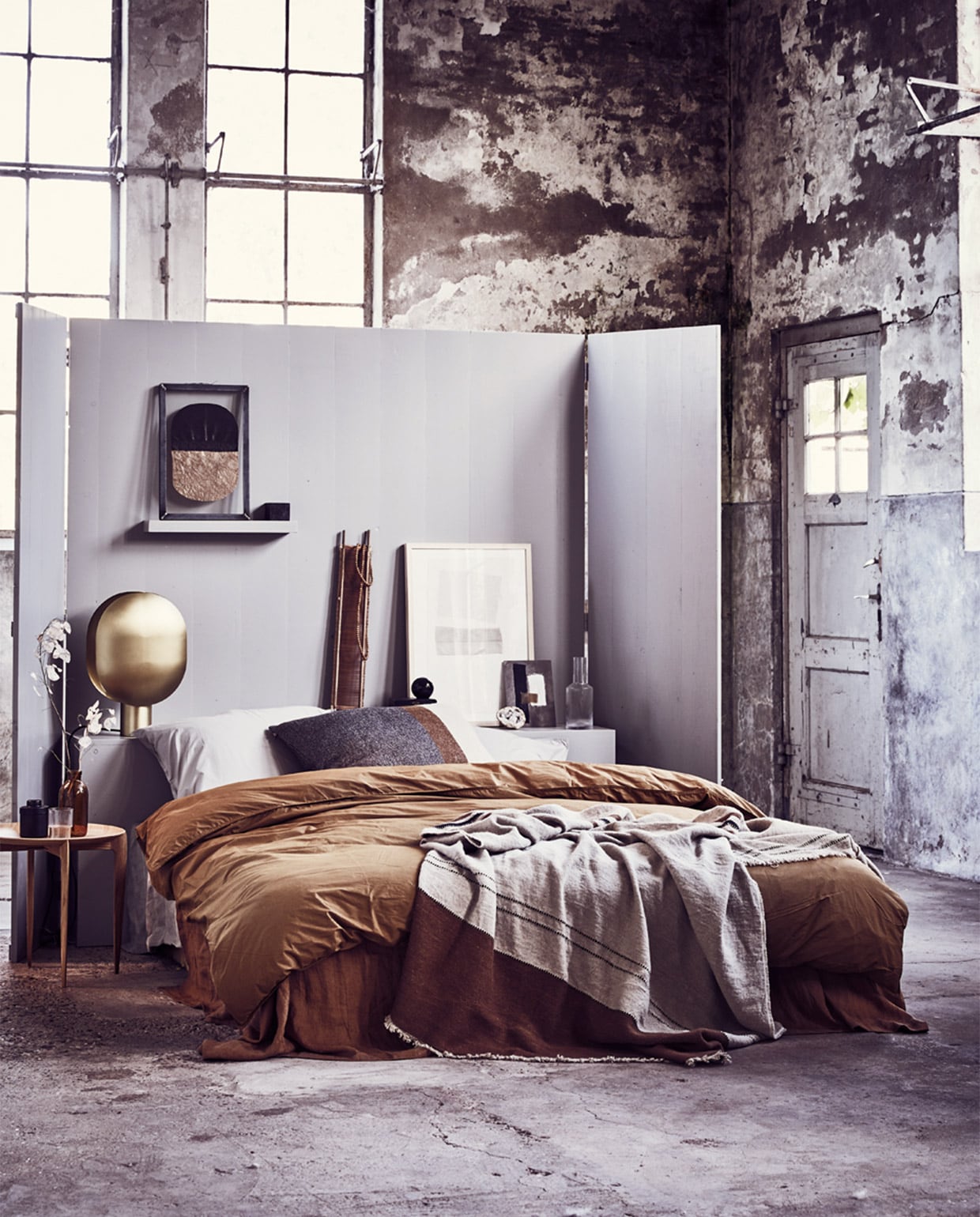 Headboard/kamerscherm (Combitex). Grote lijst met ingelijste textielkunst van Fant, klein kunstwerk op karton van Birgitta de Vos, houten ketting (Sukha Amsterdam). Kunstwerk in stalen frame met papier van Laura de Wilde X Lola Kate 03 (Laura de Wilde). Gestreepte sprei van Libeco van linnen en wol, bruin gestreept kussen 63×63 cm (Couleur Locale). Linnen laken, kaneelkleur, 260×300 cm (By Mölle). Dekbedovertrek perkal katoen, kaki-goud zonder kussenslopen, 220×240 cm, kussenslopen zilvergrijs, 70×60 cm (suite702.com). Glazen karaf, glas van Ferm Living set van 4, zwart potje met deksel (Six and Sons). Salontafel Tray Table van Fritz Hansen (Mobilia). Messing lamp Clamp van Norr11 (Melchior Interieur). Smalle houten zeef (Aura Peeperkorn). Overig privébezit. JA | vtwonen 13-2018 | styling Cleo Scheulderman | fotografie Jeroen van der Spek