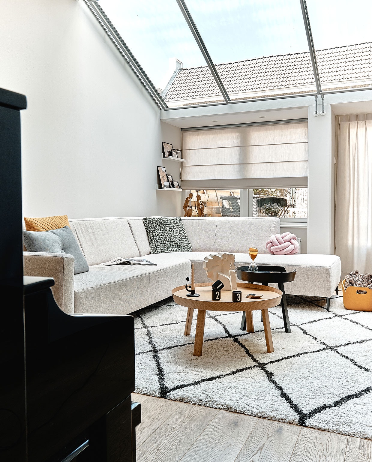 Muurverf Ammonite van Farrow &amp; Ball. Bank Goossens. Grijs en geel kussen Hay, bolletjeskussen 2LIF en knoopkussen Westwing. Vloerkleed Benuta. Salontafels en gele opbergbak Muuto, kandelaar Ferm Living, espressokopjes Design Letters. Beeld Alain Hubinont en houten beelden in vensterbank van Maartens ouders. Zandloper Hay. vtwonen 05-2022 | productie Cocofeatures | fotografie Roos Oosterbroek