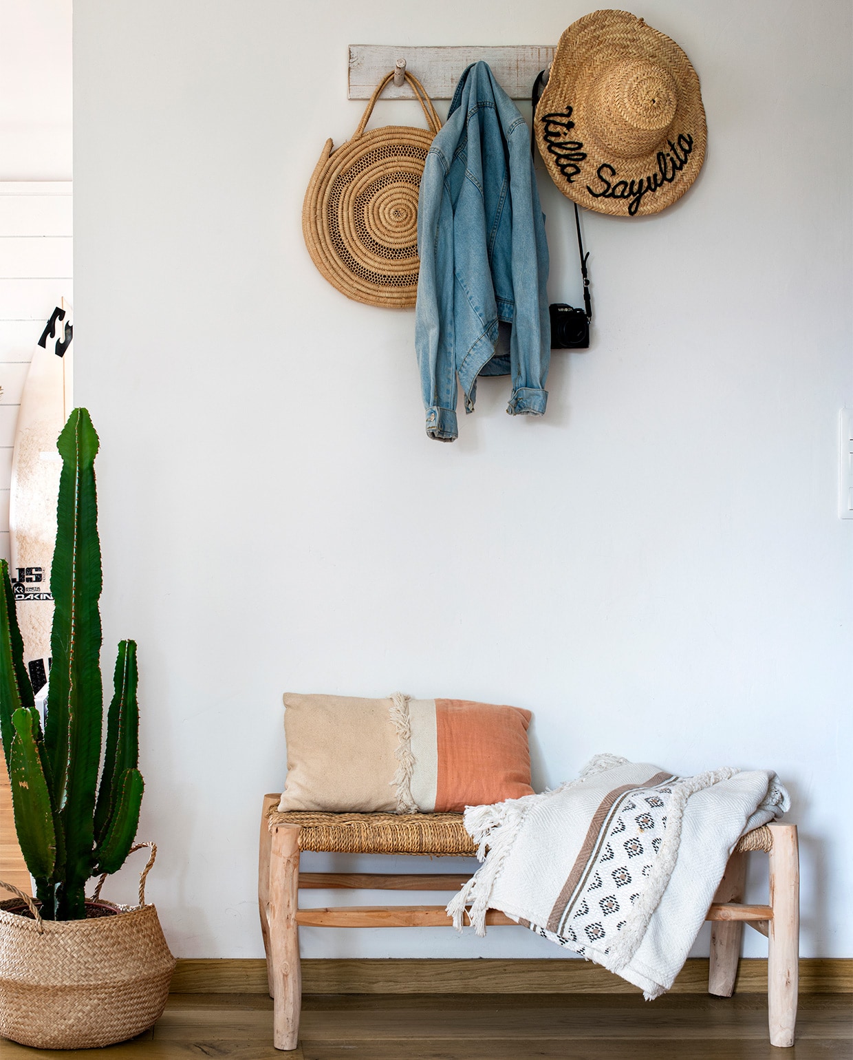 Houten bank met gevlochten zitting, plaid, kussen en plantenmand Pompon Decoration Shop in Waterloo. Kapstok door Sam gemaakt. Overig onbekend. vtwonen binnenkijk special 07-2021 | productie &amp; tekst Anne-Catherine Scoffoni | styling Catherine Cornille | fotografie Patrick Sordoillet