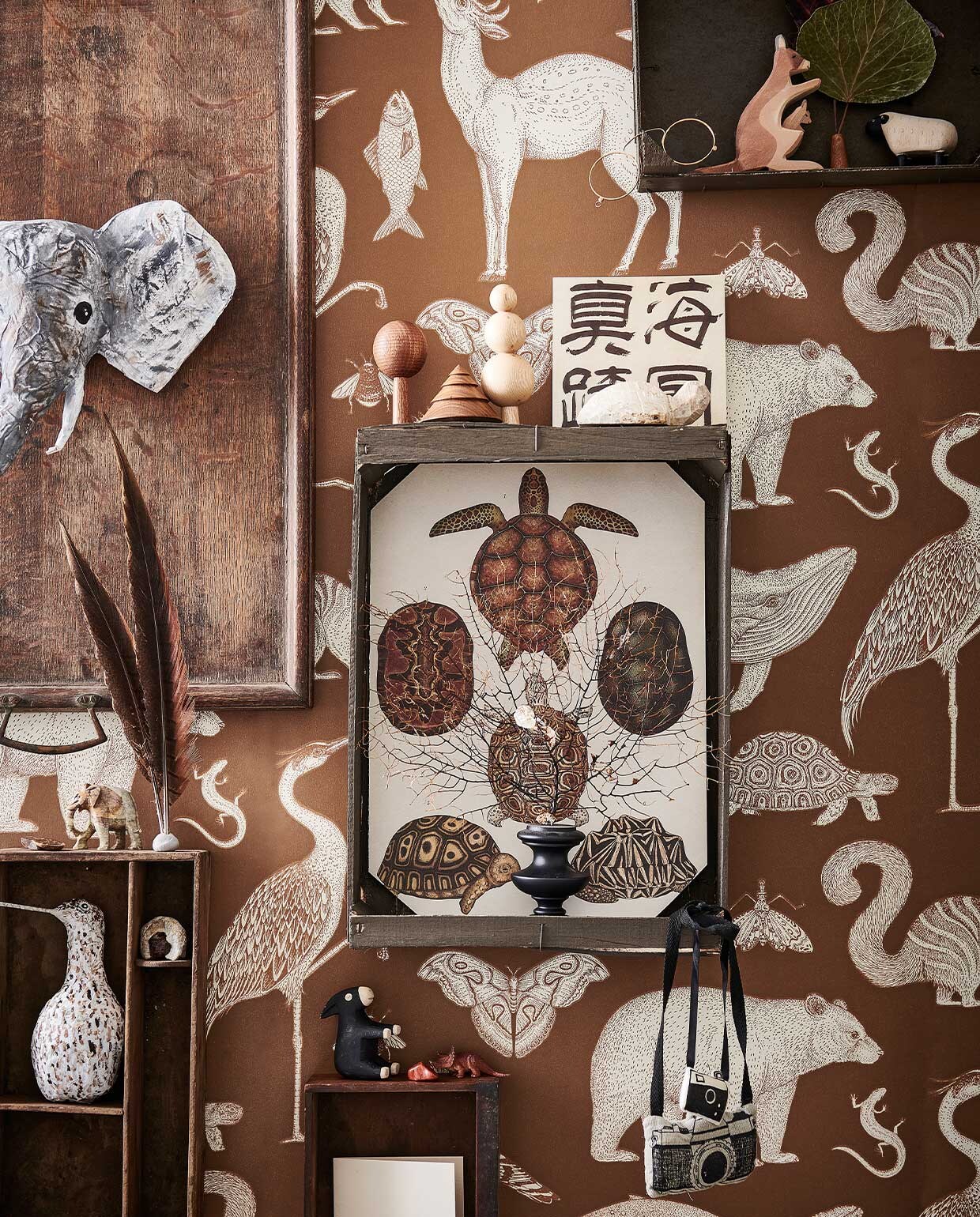 Behang Animals van Katie Scott in kleur Toffee € 99,- (fermliving.com). Oud houten dienblad € 45,-, houten lade € 10,- (burbri.nl). Houten kistjes van de groenteboer geschilderd in Peppery Black No. 71 (vestingh.nl). Handgemaakte houten boompjes € 19,50 (bymolle.com). Papier-maché olifant en grutto gemaakt door Babette Hofstede, prijs op aanvraag (babetteswereld.com). Soapstone Animal Shape schildpad € 5,75, stenen vanaf € 4,25 (iine.nl). Houten kangoeroe € 13,50, houten ezel en schaap vanaf € 11,95 (ilovespeelgoed.nl). Zwart koraal € 130,- (allestedlund.com). Beeldje olifant kringloopvondst. Overig privébezit. vtwonen 13-2021 kids special | styling Kim van Rossenberg | fotografie Sjoerd Eickmans | Assistentie Sanne van der Beek, Judie Jonker, Kim Suos\n