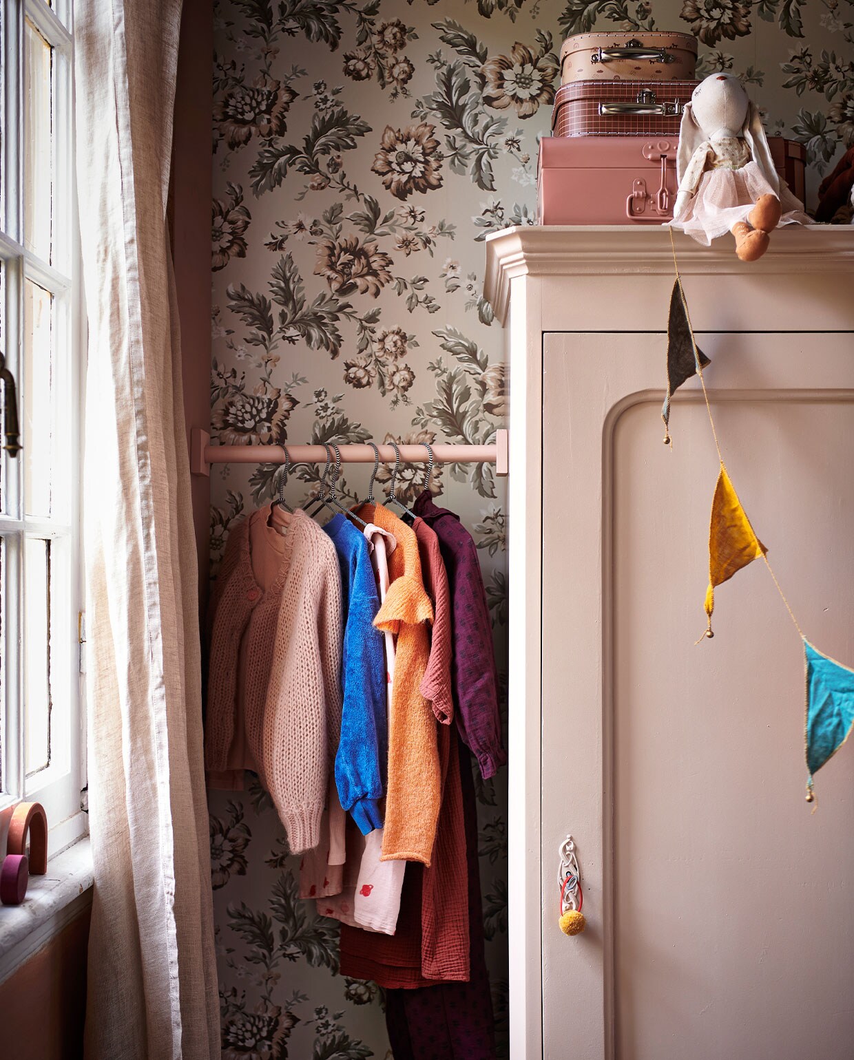 Behang Rosenholm Wheat van Sandberg € 111,56 (sandbergwallpaper.com). Beige linnen gordijnen € 69,99 (hm.com). Lichtroze kast prijs op aanvraag (com-anders.nl). Roze koffer van Bonton € 29,-, set koffertjes met print van Oyoy Living Design € 24,90 (storeofdaydreams.com). Knuffel konijn € 22,99 (zarahome.com). Houten gekleurde blokken van Raduga Grez € 139,- (archive-store.nl). Houten stok geschilderd in de kleur Light Peachblossom (littlegreene.nl). Kleding (fishonthemoon.com). Stoffen slinger multicolour van Numero 74 € 17,- (archive-store.nl). JA vtwonen 13-2021 kids special | styling Kim van Rossenberg | fotografie Sjoerd Eickmans | Assistentie Sanne van der Beek, Judie Jonker, Kim Suos\n