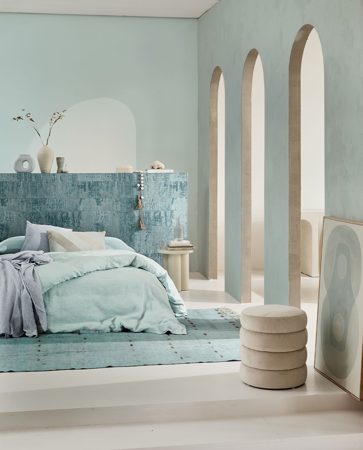 Behang Atelier d’Artiste Brumes Existentielles VP 880 23 van Elitis, per rol van 1×10 m € 241,- (elitis.fr). Linnen dekbedovertrek Pale Blue, 220×240 cm € 325,-, linnen laken Scandinavian Blue, 320×270 cm € 235,-, katoenen sprei Sky Blue, 140×220 cm € 139,-, lichtblauwe handgeknoopte hennep kelim, 291×184 cm € 1095,- (couleurlocale.eu). Fluwelen poef Alto, 42×47 cm € 99,- (westwingnow.nl). Kruk Noo.ma Oly in Piazza Beige € 289,-, lichtblauwe vaas van HKliving € 32,30, lichtblauw gestreept kussen, 40×60 cm van HKliving € 30,60, sierkussen Outline van Hay in Ice Blue € 55,99, karaf Ripple van Ferm Living € 39,- en glazen Ripple van Ferm Living, set van 4 € 35,- (vtwonen.nl). Schilderij Longing for, acryl op canvas van Anne Olde Kalter, 70×100 cm prijs op aanvraag (anneoldekalter.com). Op de muur krijtverf Estate Emulsion Skylight 205 van Farrow &amp; Ball, 2,5 liter € 97,- (paint-paper.nl). Overig privébezit. NEE | vtwonen 04-2022 | Styling Cleo Scheulderman | Fotografie Jeroen van der Spek | Assistentie Krystel-Jane Robinson, Jamaine Festen