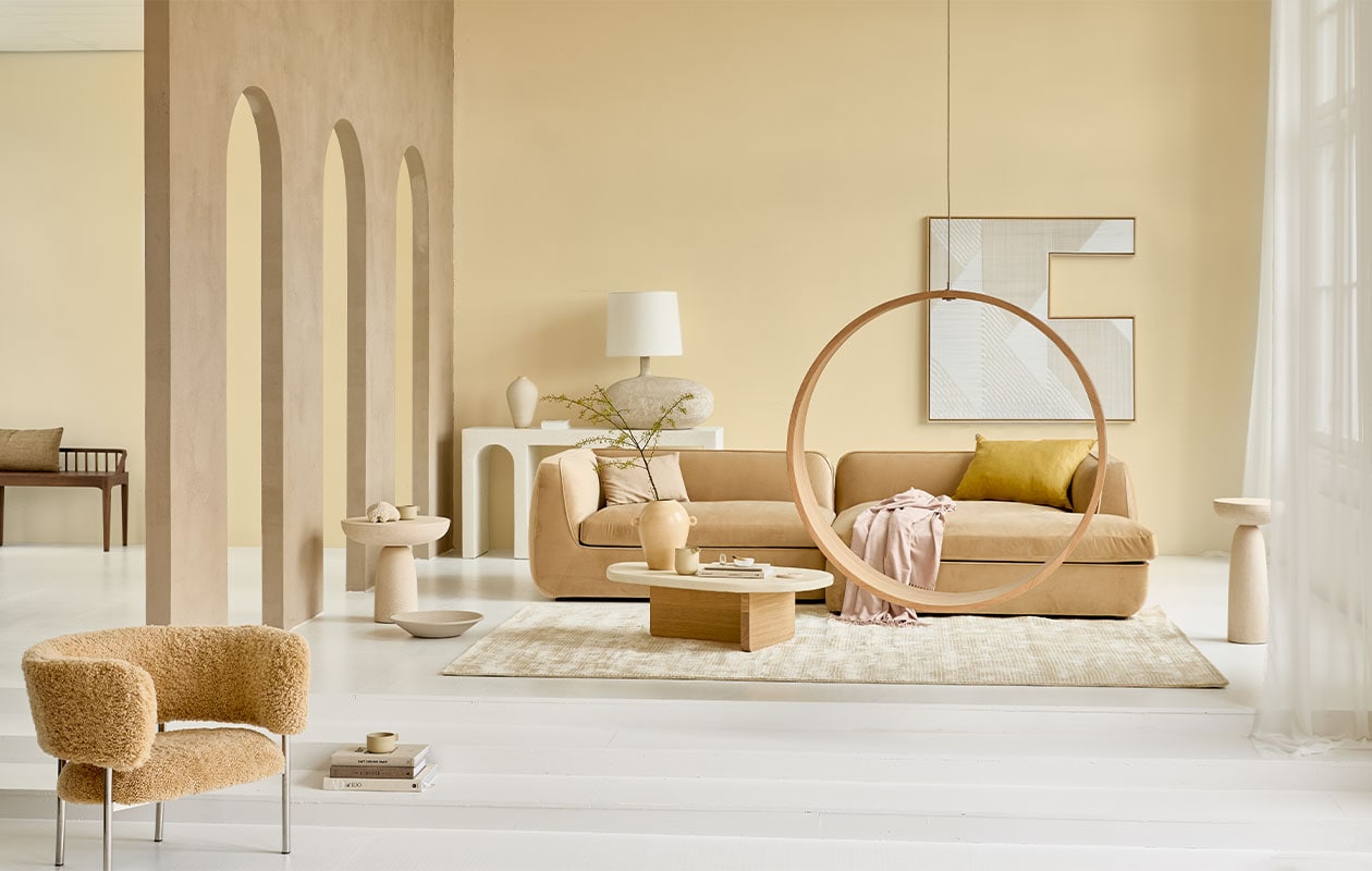 Op de muur krijtverf Estate Emulsion Farrow’s Cream 67 van Farrow &amp; Ball, 2,5 liter € 97,- (paint-paper.nl). Bank Bowie Juke Sand corner sofa divan right, 296x170x72 cm vanaf € 3108,- (festamsterdam.com). Microcement sidetable vanaf € 1850,-, schemerlamp € 590,- (lanena-home.com). Fauteuil Font Bold van Møbel-Copenhagen bekleed met honinggele schapenvacht € 3231,- (roosdesign.eu). Salontafel Mush met eikenhouten onderstel en gesmeerd blad, 105x60x30 cm (lxbxh) € 649,- (aedamanthony.nl). Ronde eikenhouten hangstoel Swing no 2 van Iwona Kosicka, prijs op aanvraag (kosicka.pl). Viscose vloerkleed met ingeweven streepreliëf van HKliving, 300×200 cm € 845,75 (vtwonen.nl). Gele vaas € 69,95 (urbannatureculture.com). Mok, set van twee vanaf € 90,-, kan van gedraaide klei vanaf € 70,- (byjoa.nl). Linnen kussen, 50×70 cm € 120,- (couleurlocale.eu). Microcement bijzettafels, 50×50 cm € 702,-, 30×61 cm € 618,- (edha-interieur.nl). Kunstwerk aan de muur van Matthias de Vogel, 120×120 cm prijs op aanvraag (faultlineslab.com). Roze plaid € 49,99, katoenen kussenhoes, 30×50 cm € 7,99 (zarahome.com). Houten bank Oak Spindle, 150x35x60 cm (bxdxh) € 669,- (ethniccraft.com). Overig privébezit. NEE | vtwonen 04-2022 | Styling Cleo Scheulderman | Fotografie Jeroen van der Spek | Assistentie Krystel-Jane Robinson, Jamaine Festen