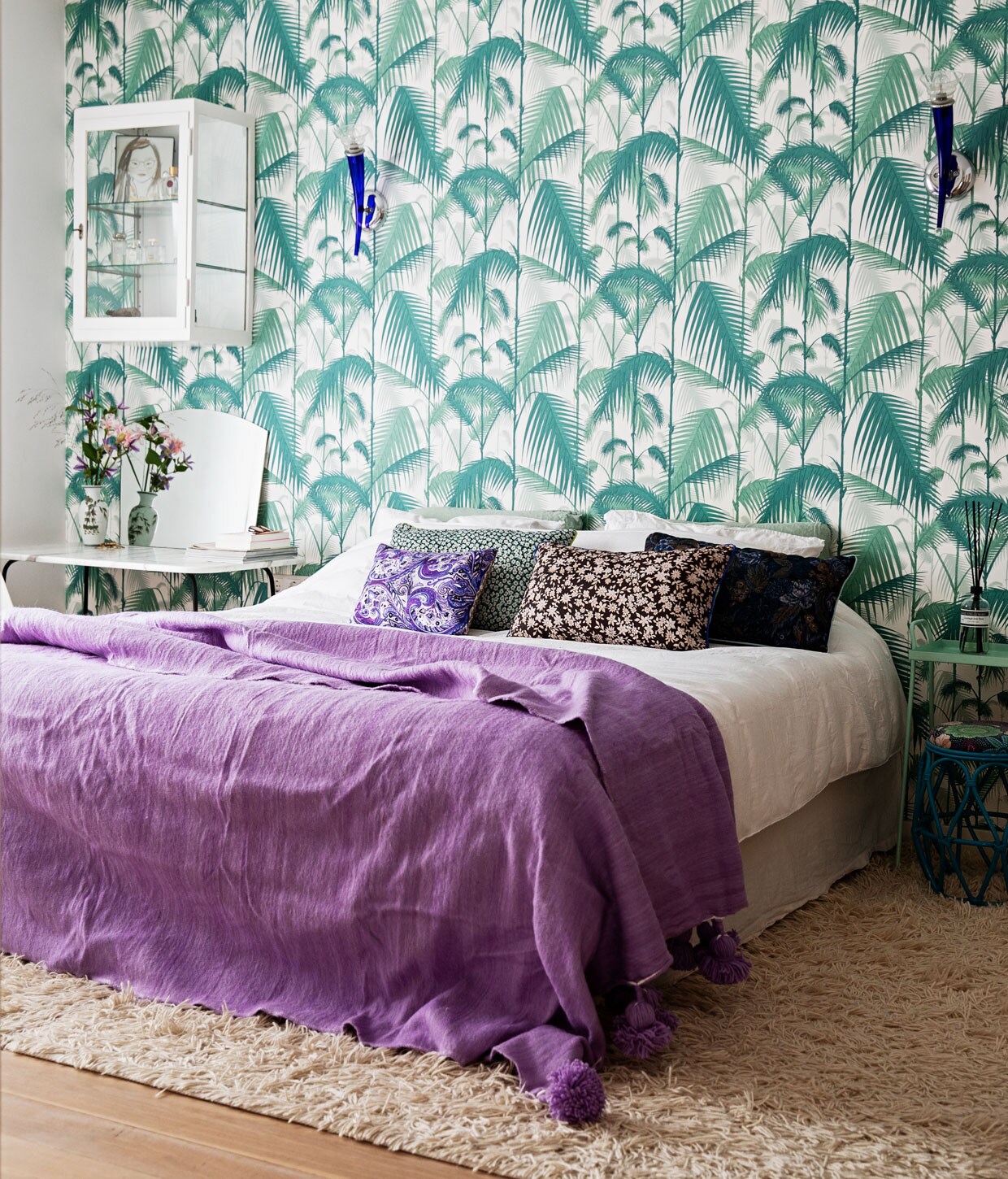Behang Palm Jungle F111/2005 Cole &amp; Son, bed boxpring Eastborn, wandlampen gekregen van Nicolettes ouders, handgemaakte berber pompomdeken The Souks, wit beddengoed Four Leaves, vloerkleed Ikea, kussens Doris voor HKliving, vloer whitewashed eikenvloer De Oude Plank, groen tafeltje Loods 5, krukje Rice vintage, geurstokjes Marie-Stella-Maris. vtwonen 12-2020 | Styling Ilona Jongepier | Fotografie Dana van Leeuwen |