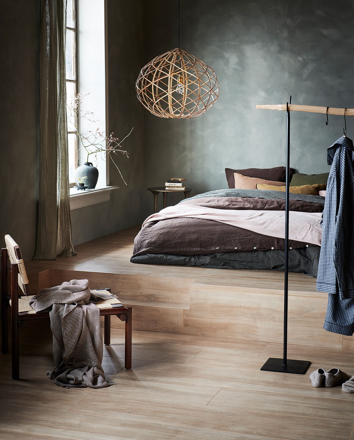 kliklaminaat uit de vtwonen collectie, Laminaat XL Rafter naturel, lamel 138×32,6×0,8 cm met groef, inhoud pak 5 stuks voor| M.m.v. mimiettoi.com (walnut armless chair), zarahome.com (geruit dekbedovertrek, geruite pyjama, sloffen, wollen plaid, groene vaas, zwart schoteltje, groen gordijn, roze plaid), couleurlocale.eu (hanglamp, aluminium tafel Honey van Tine K Home, houten kledingrek met metalen steunen, donkerbruin linnen dekbedovertrek, kussens vice versa black line), vestingh.nl (kalkverf Lab Eco Chalk in kleur Dancing Leaves No. 89). Overig privébezit. vtwonen 03-2022 | productie Tanja Saarberg | styling Kim van Rossenberg | fotografie Sjoerd Eickmans