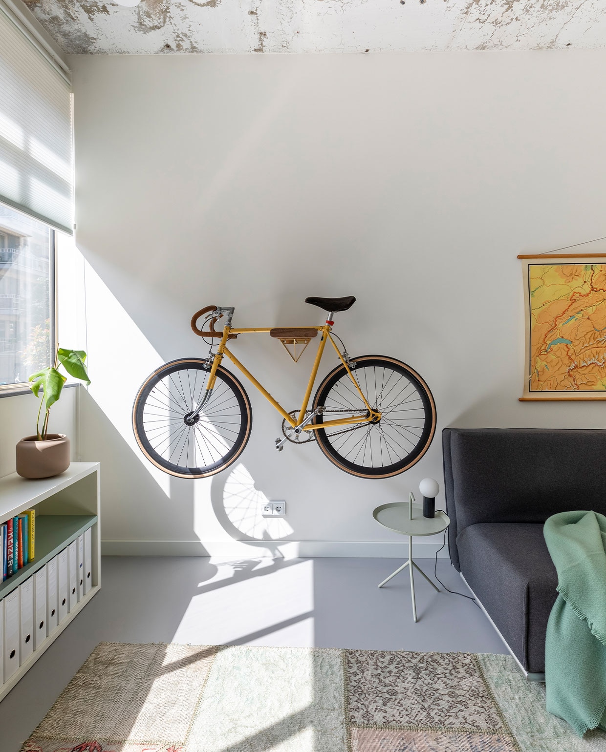 Fiets refurbished door Lievens Bikes. Slaapbank Natalie van Pfister (Zwitserland). Bijzettafel Hay. Lage kast met eraan vast bureau Sangiacomo, op maat gemaakt door Combo Design. Schoolkaart Zwitserland vintage. Vloerkleed patchwork van oude, geverfde Perzische tapijten. vtwonen 03-2022 | fotografie Margriet Hoekstra