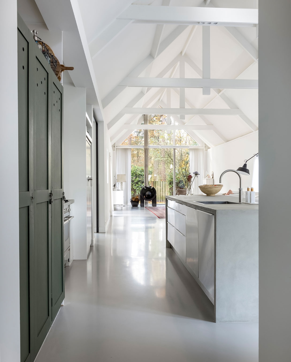 Keuken Ikea, keukenblad krasvaste gietvloer van lavasteen, kleur beton, Poolse legerkast vintage, krijtverf legerkast in kleur Verruiming van Histor, fruitschaal Loods 5, kraan Quooker, koelkast en fornuis Boretti, zeep en handcrème Rituals, mand met hout Kwantum. vtwonen 04-2022 | fotografie Henny van Belkom