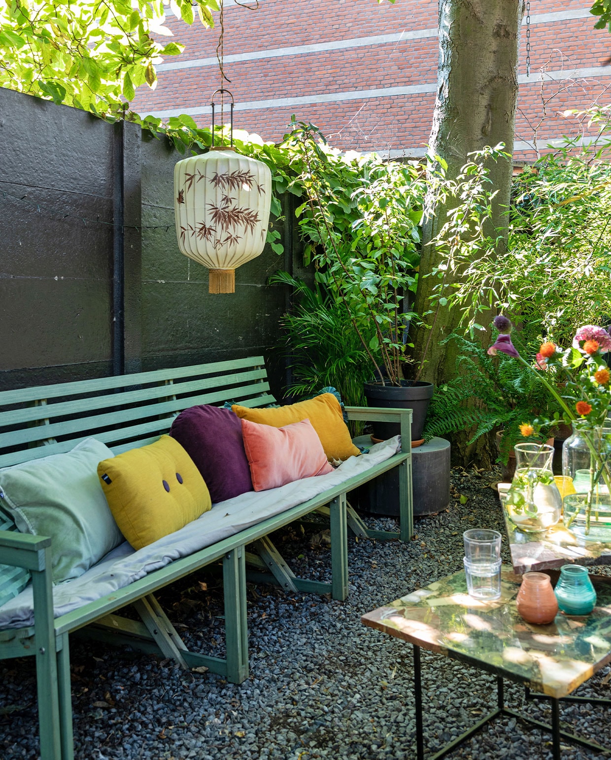 Bank Weltevree. Linnen dekbedovertrek By Mölle. Kussens van links naar rechts: HKliving, Hay, Sissy-Boy, Søstrene Grene, H&amp;M Home. Lampion HKliving. Betonnen ronde bijzettafel House Doctor, vierkante bijzettafels en karaf vintage. Buitenkaarsen Bolsius, glazen Serax, vaas vtwonen. vtwonen TUIN special 3 | Styling Theo-Bert Pot, Jelle Van de Schoor | fotografie Theo-Bert Pot | tekst Cathelijne van Wingerden
