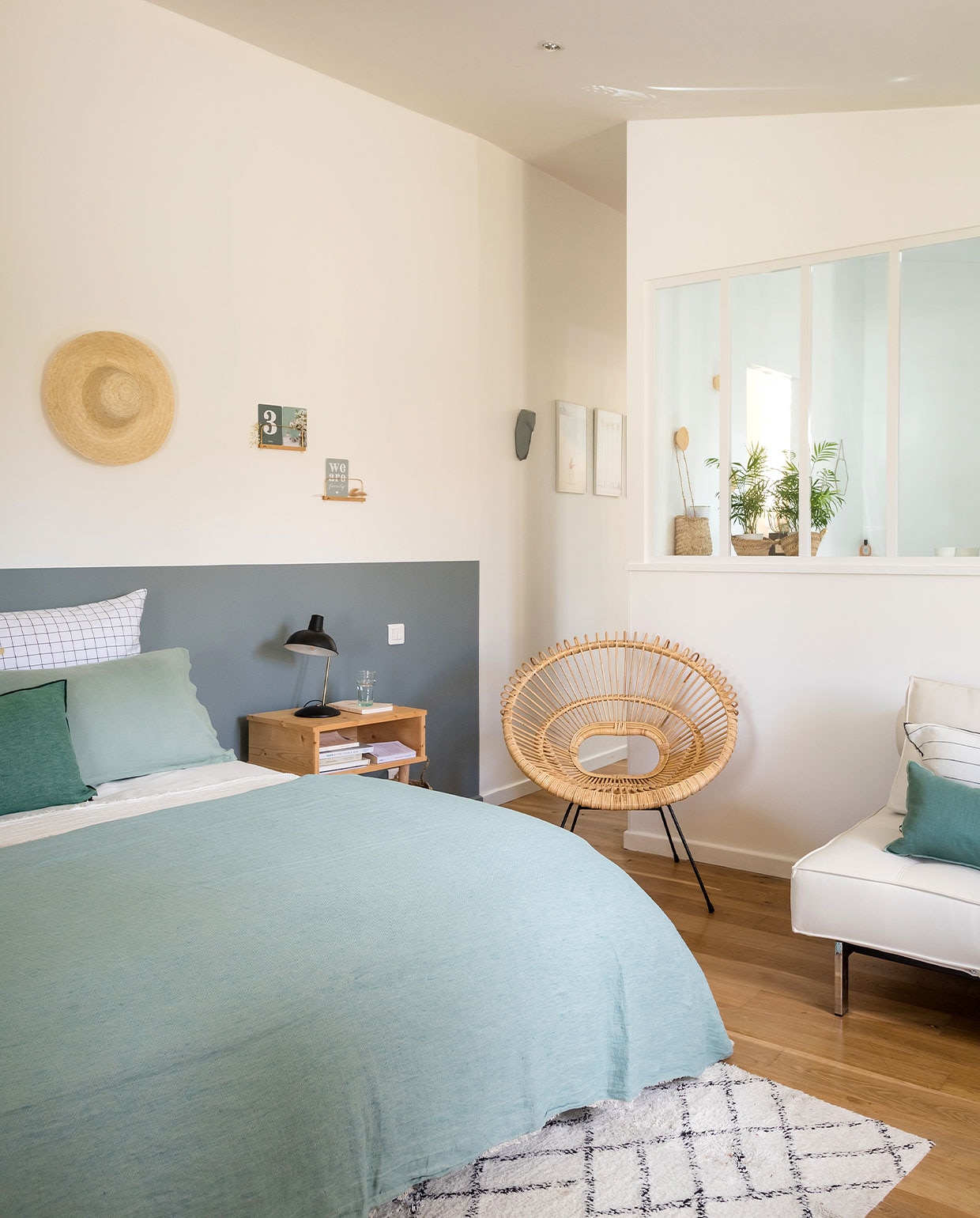 Grijze muurverf Breutter Grew van Benjamin Moore, bedlinnen Harmony Textile, plaid en groene kussens Maison de Vacances, tapijt Søstrene Grene, stoel 4murs. Overig onbekend. vtwonen 04-2022 | productie AC Scoffoni | styling Marie Maud Levron | fotografie Cecile Perrinet Lhermitte