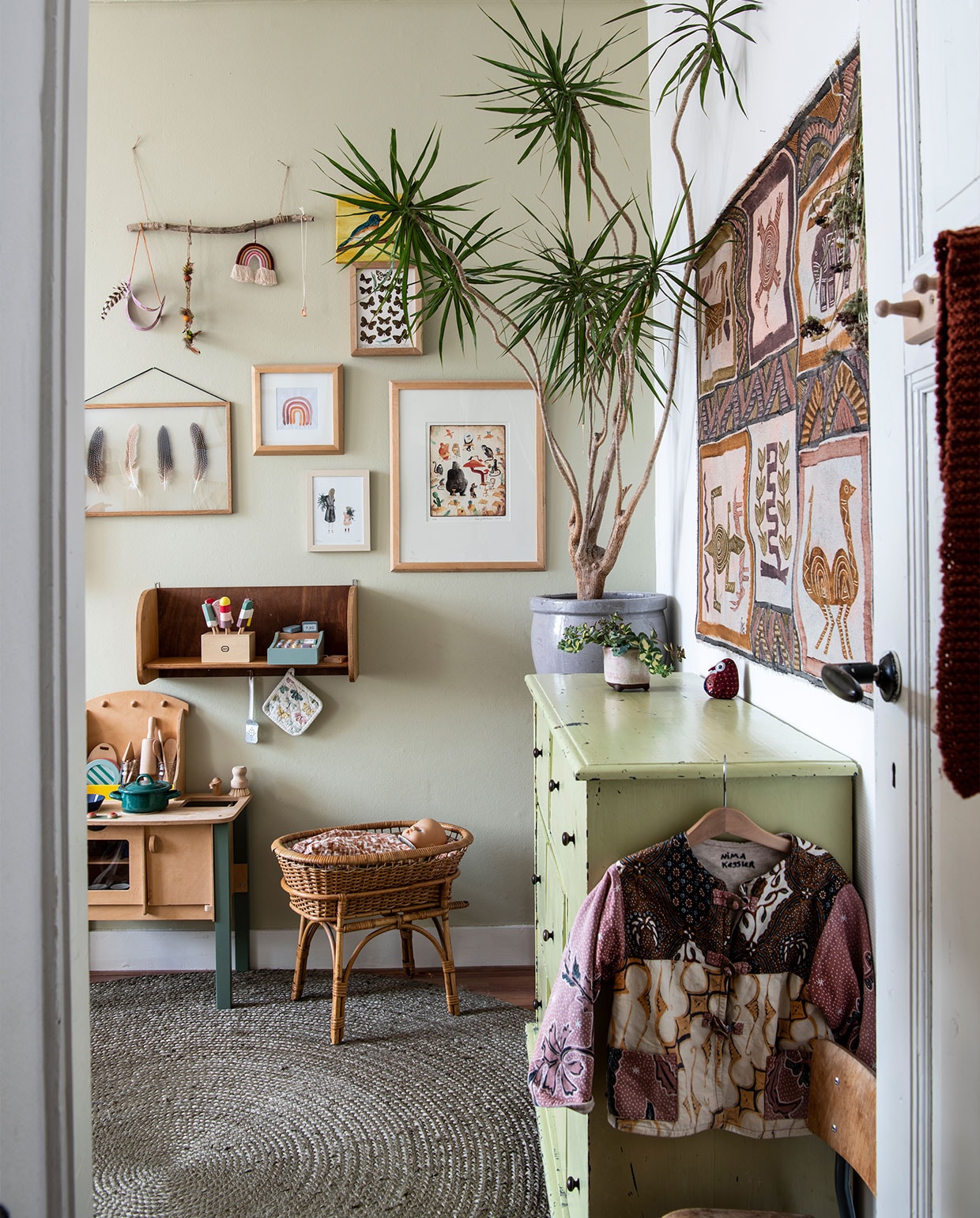 Ladekast, rieten poppenwieg, houten wandplank, plantenpotten tweedehands. Speelkeuken Marktplaats. Lijsten Fine Store, veren Hopi-Navajo. Regenboogprint Zoë, moeder &amp; dochter Saar Manche, dieren Marije Tolman. Kleed Woon Express. Wandkleed Marktplaats. Muurverf Toegankelijk van Histor. Planten Dracaena, sedum. Overig herkomst onbekend. vtwonen 02-2022 | productie Insidehomepage | styling Inge van Lieshout | fotografie Louis Lemaire