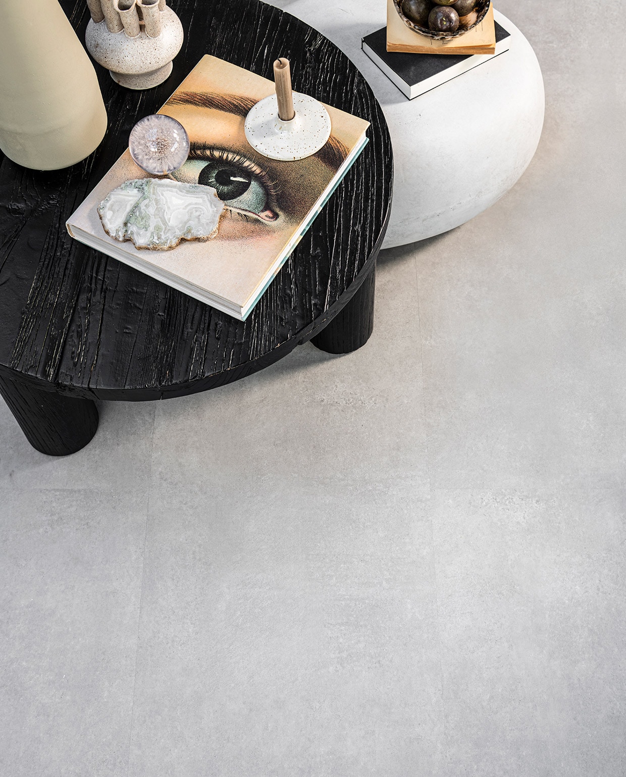 PVC Vloer Basic Light Grey, 91,4×45,7 cm, dryback per m² € 41,95, click per m² € 54,95.M.m.v. loods5.nl (zwarte salontafel van Loods 5 Goods), basiclabel.nl (bijzettafel Pebble betonlook van vtwonen), sissy-boy.com (zachtgroene vaas, vaas met meerdere halzen, kristal, gemarmerde kom), letoile.store (presse papier bloem, kandelaar). Overig privébezit. JA vtwonen 06-2021 | Styling Danielle Verheul | Fotografie  Sjoerd Eickmans | Productie Tanja Saarberg