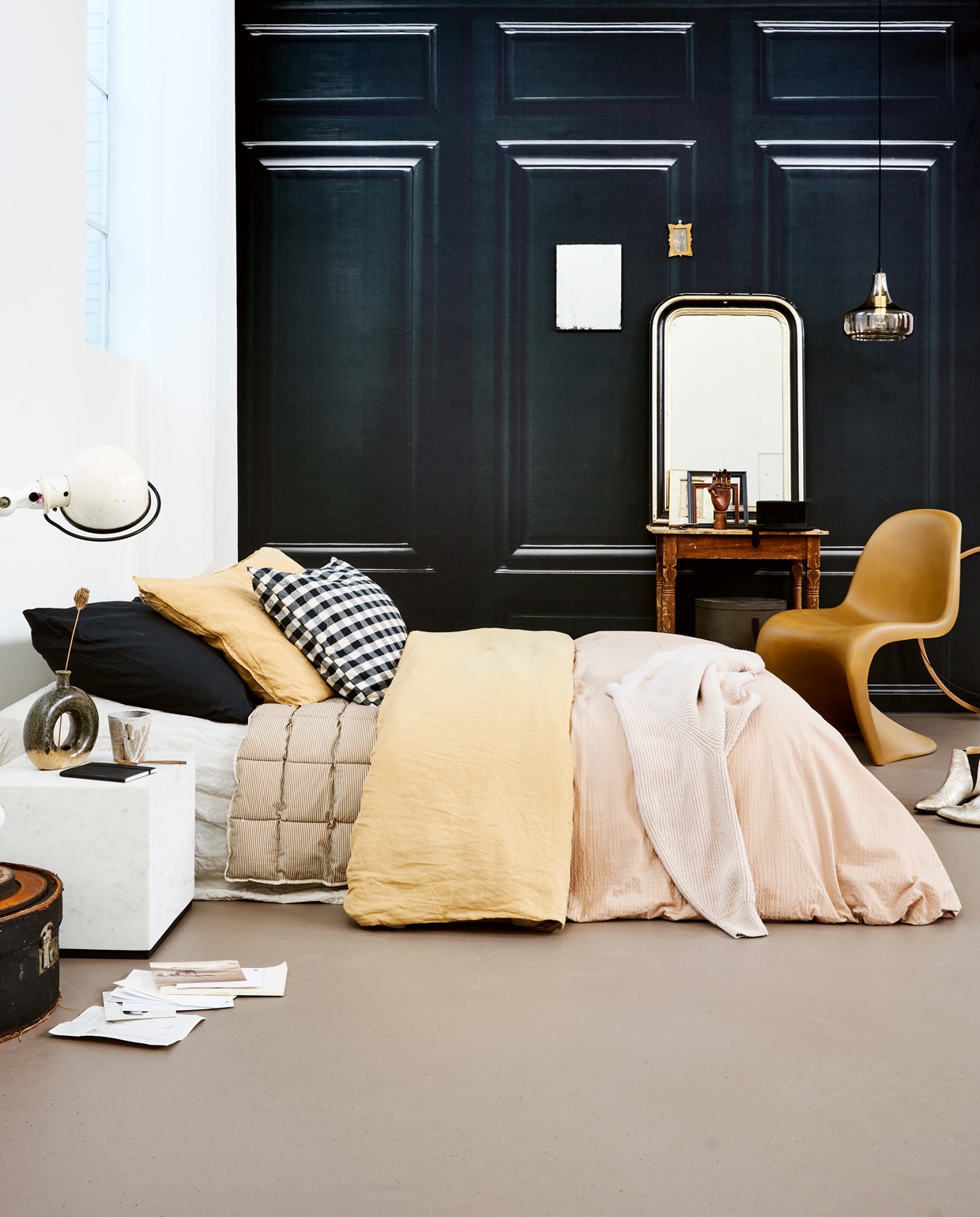 Marmoleum vloer kleur Leem vtwonen 04, per m² € 48,-. M.m.v. behangfabriek.com (zwart behang Wood Paneling), householdhardware.nl (polyester S-chair), jolandelijkdewebshop.nl (tafel, spiegel, hoedendozen, houten hoepel, gouden lijst, witte Jieldé-lamp), hkliving.nl (marmeren salontafel, verouderde spiegel), sissy-boy.com (mok), sostrenegrene.com (houten hand), vtwonen.nl (vaas, dekbedovertrek, hanglamp), hm.com (zwarte kussenslopen, okergele dekbedovertrekset), littledreamers.nl (dekbed met streep). Overig privébezit. vtwonen 01-2022 | productie Tanja Saarberg | styling Marlies Does | fotografie Bart Brussee | assistentie Judie Jonker