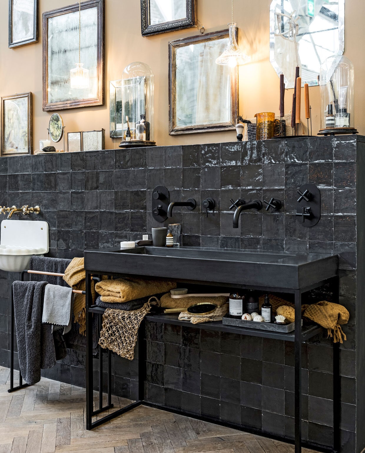 Stalen kozijn prijs op aanvraag (exclusivesteel.nl). Visgraatvloer van eikenhout met boenwas (oudeplank.nl). Muurverf kleur Thatch van Bauwerk (wearewowmakers.com). Lambrisering van tegels Craft van vtwonen by Douglas & Jones, kleur Off Black, 12,5x12,5 cm (vtwonentegels.nl). Douchegordijn van stof (de-stoffeerder.nl). Nieuw klassiek bad (douchezaak.nl). Antiek bad, prijs op aanvraag (oudebouwmaterialen.nl). Antieke en nieuwe spiegels op wand (weldaad.nl, affairedeau.com, loods5.nl, burbri.nl, badenbaden.nl). Antieke wastafel op poot (oudebouwmaterialen.nl). Messing wandkraan (affairedeau.com). Hardstenen kasteelbakje, in diverse maten prijs op aanvraag, oude messing wandkraan (oudebouwmaterialen.nl). Hanglampen van Lee Broom prijs op aanvraag (eikelenboom.nl). Okergele en antracietgrijze handdoeken (badenbaden.nl). Grijze handdoek met zwarte sierrand (maisonnl.com). Katoenen okergele handdoeken van Zusss (vtwonen.nl). Antracietgrijze wafeldoek, glazen box met messing (hm.com). Antieke, glazen stolpen (burbri.nl). Zwart metalen blad (badenbaden.nl). Amber geurblokje, set van 2 (maisonnl.com). Zwarte, ronde geurbox, waxinelichthouder met vergrootglas (artilleriet.se). Beautyproducten van de merken Aesop, Diptyque, LeLabo en Susanne Kaufman prijs op aanvraag (skins.nl). Natuursponzen, honingraat zeepjes, cederhoutballetjes (dille-kamille.nl). Zwarte kandelaar (bymolle.com). Overig privébezit. vtwonen bijlage woonbeurs 13-2018 | fotografie Sjoerd Eickmans | styling Cleo Scheulderman