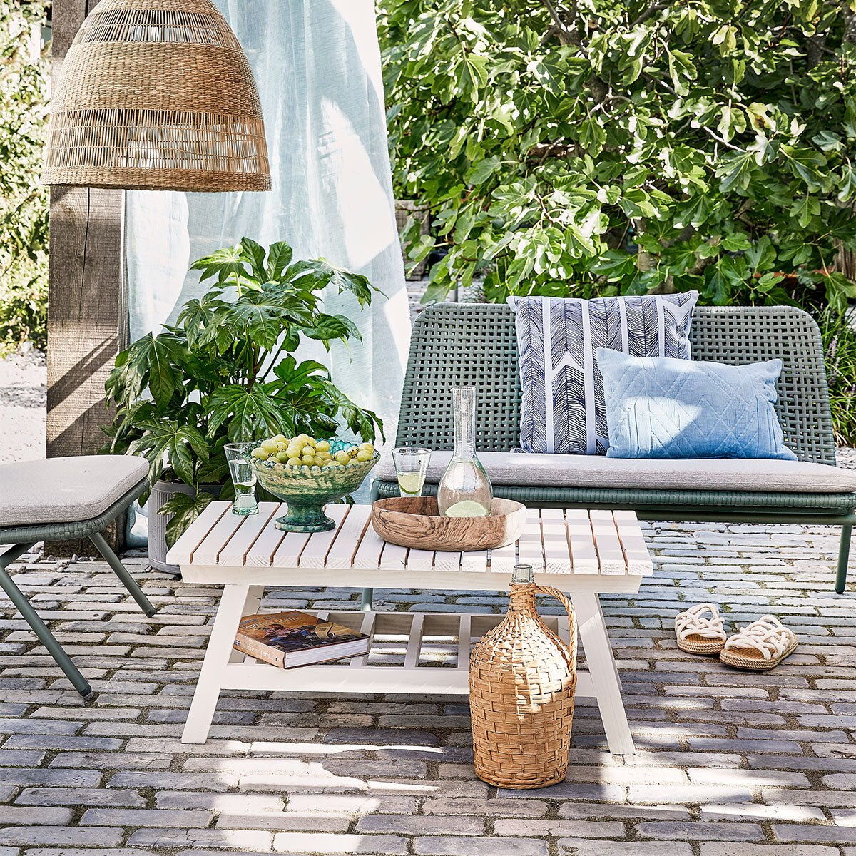 Bank Wivinia € 419,- en stoel Wivinia € 211,50 van Kave Home (vtwonen.nl). Gordijn gemaakt van linnen stof per meter € 25,- (ochreandred.nl). Kussen met print Heringbone € 25,95, lichtblauw kussen Naida € 19,99 (intratuin.nl). Schaal op voet € 99,95, walnoothouten schaal € 75,-, glazen karaf Cigogne € 23,50, glazen op voet Diabolo per stuk € 6,80 (householdhardware.nl). Instappers € 35,99 (zarahome.com). Rieten lamp Torared € 39,95 (ikea.com). Plaid Native Fan € 34,99 (sissy-boy.com). Sisal kussen € 25,- (loods5.nl). Overig privébezit. vtwonen tuin special 4-2021 | productie Corrien Flohil | uitvoering Johan Snoodijk @snoodijkencostyling Moniek Visser | fotografie Peggy Janssen
