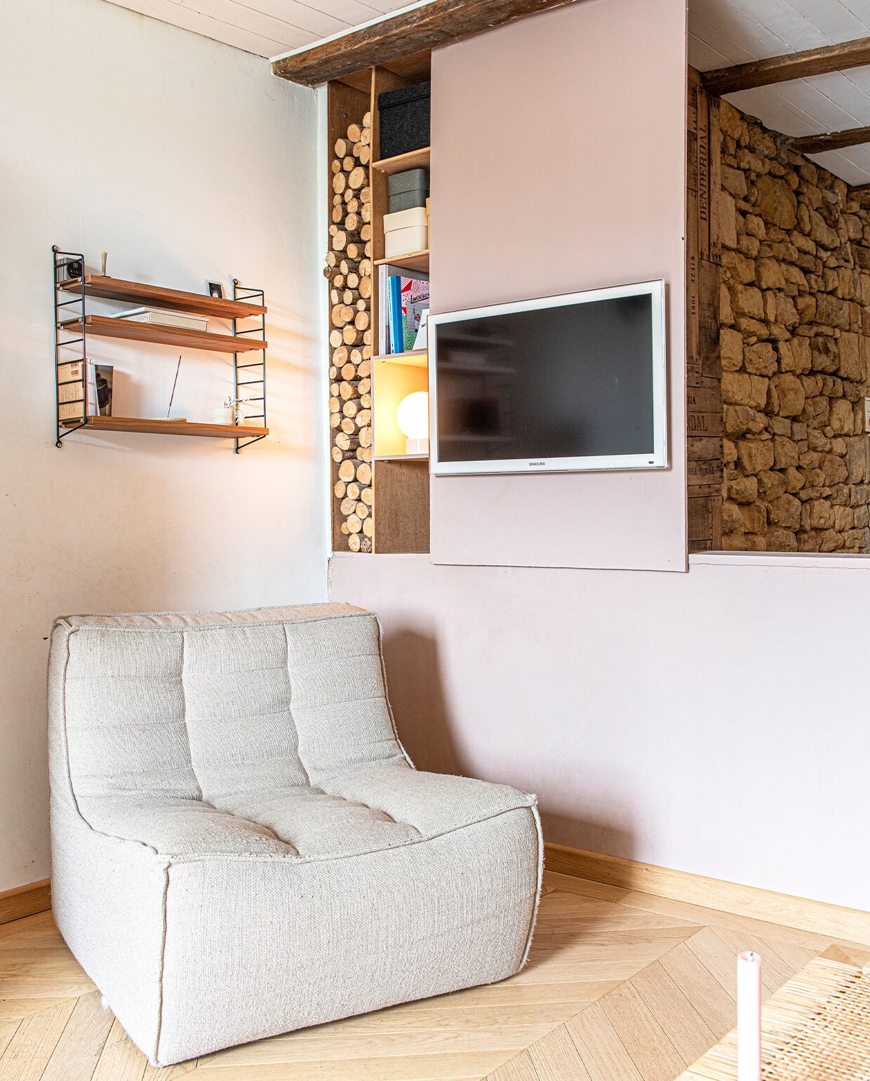 Fauteuil Ethnicraft, wandrek String Furniture, vloer eiken parket, televisie Samsung, kandelaar zelfgemaakt. vtwonen 3-2022 | productie De Binnenkijkers | styling Jeske Weel | fotografie Caroline Coehorst | tekst Chris Muyres