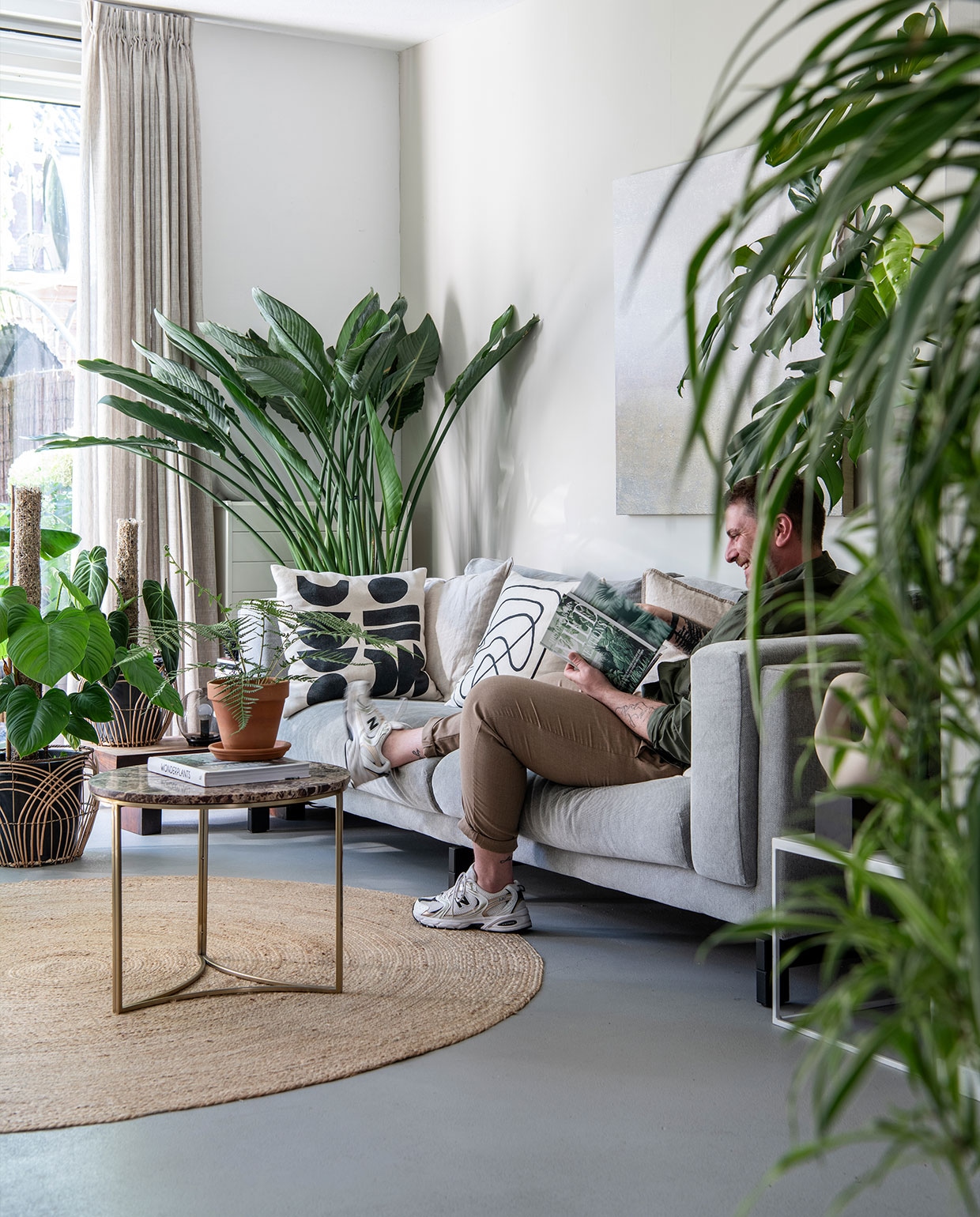 Kleed Kwantum, kussens en koffietafel H&amp;M Home, gordijnen Leen Bakker. Bank Ikea. Plantenpotten Intratuin, Xenos. Schilderij Zara Home. Planten: Strelitzia Reginae, Dicksonia Antarctica. vtwonen 3-2022 | productie Insidehomepage | styling Esther Jostmeijer | fotografie Louis Lemaire