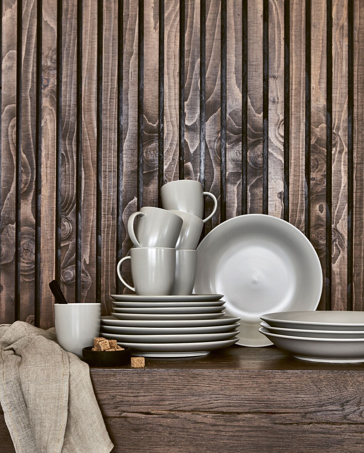 Zandkleurig mat (flax wit) porseleinen servies 16-delig € 99,-, 36-delig € 239,-. Zandkleurige theedoek met visgraatmotief, 50×70 cm € 9,95, ook verkrijgbaar in blauw en grijs. Matzwarte theelepels, set van 6 € 25,-. vtwonen 04-2022| Productie Tanja Saarberg | Styling Marlies Does | Fotografie Bart Brussee