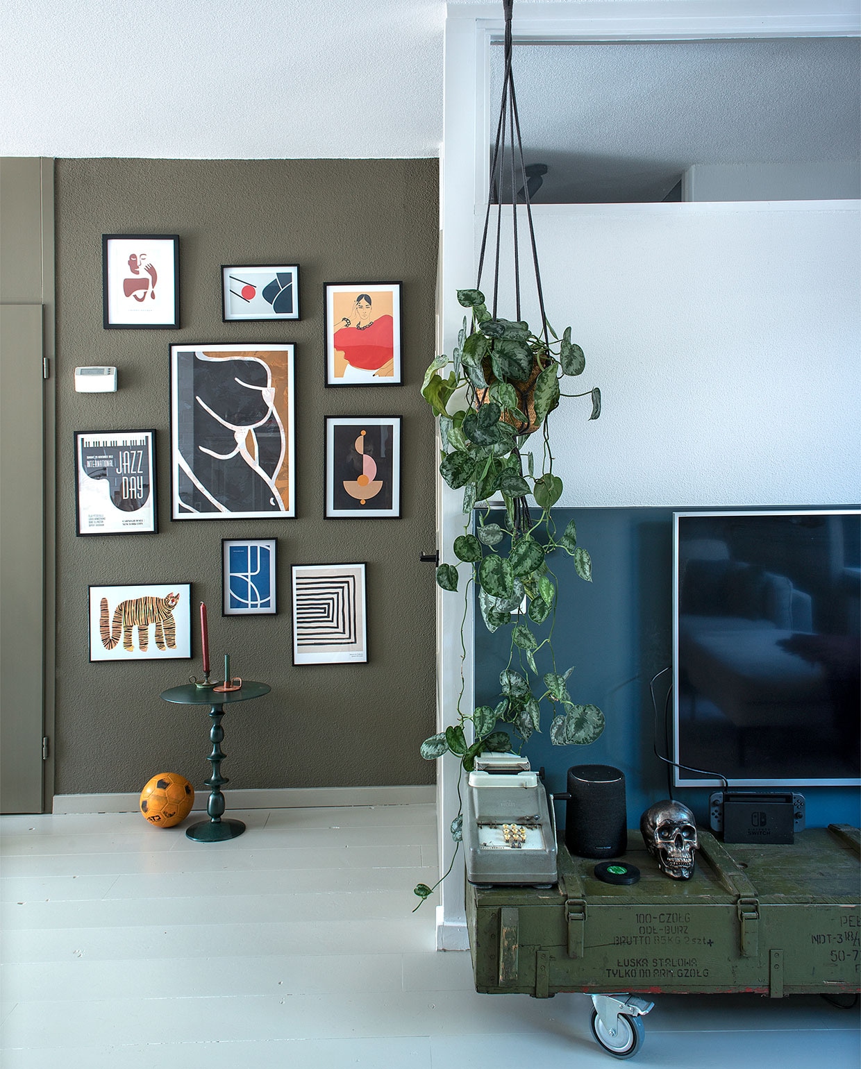 Muurverf Camouflage van Flexa en Vintage blauw van Karwei. Posters Desenio, tafel Karwei, kandelaar rechts groothandel. Speaker Harman Kardon, schedel spaarpot Kare Design. Planthanger Intratuin. Leger munitiekist, telmachine en kandelaar links van de kringloop. vtwonen DIY special 4 | Fotografie Ton Bouwer | Productie en tekst Monique van der pauw