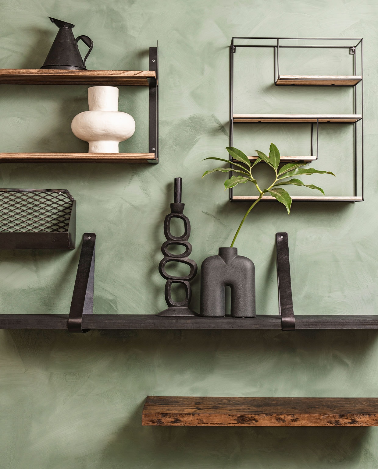 De wand is eerst behandeld met LAB Eco Chalk Primer, per liter € 44,-, daarna geverfd met LAB Eco kalkverf in de kleur Soft Fern, per liter € 54,- (vestingh.nl). Lifegoods wandplankenrek € 35,99, zwart metalen wandrek met houten plankjes van Brute Strength € 29,95, rustieke zwevende wandplank van Acaza € 31,98 (bol.com). Zwarte oliekan € 43,95 (hetkabinet.nl). Witte vaas € 68,95, kandelaar € 27,95, zwarte vaas € 55,95 (loftloft.nl). Zwart leren plankendragers € 19,95, exclusief zwarte plank (karwei.nl). Metalen gaasplank € 69,- (brut.nl). vtwonen 03-2022 | Styling Moniek Visser | Fotografie Denise Pronk| Styling assistent Sanne Kiesling\n
