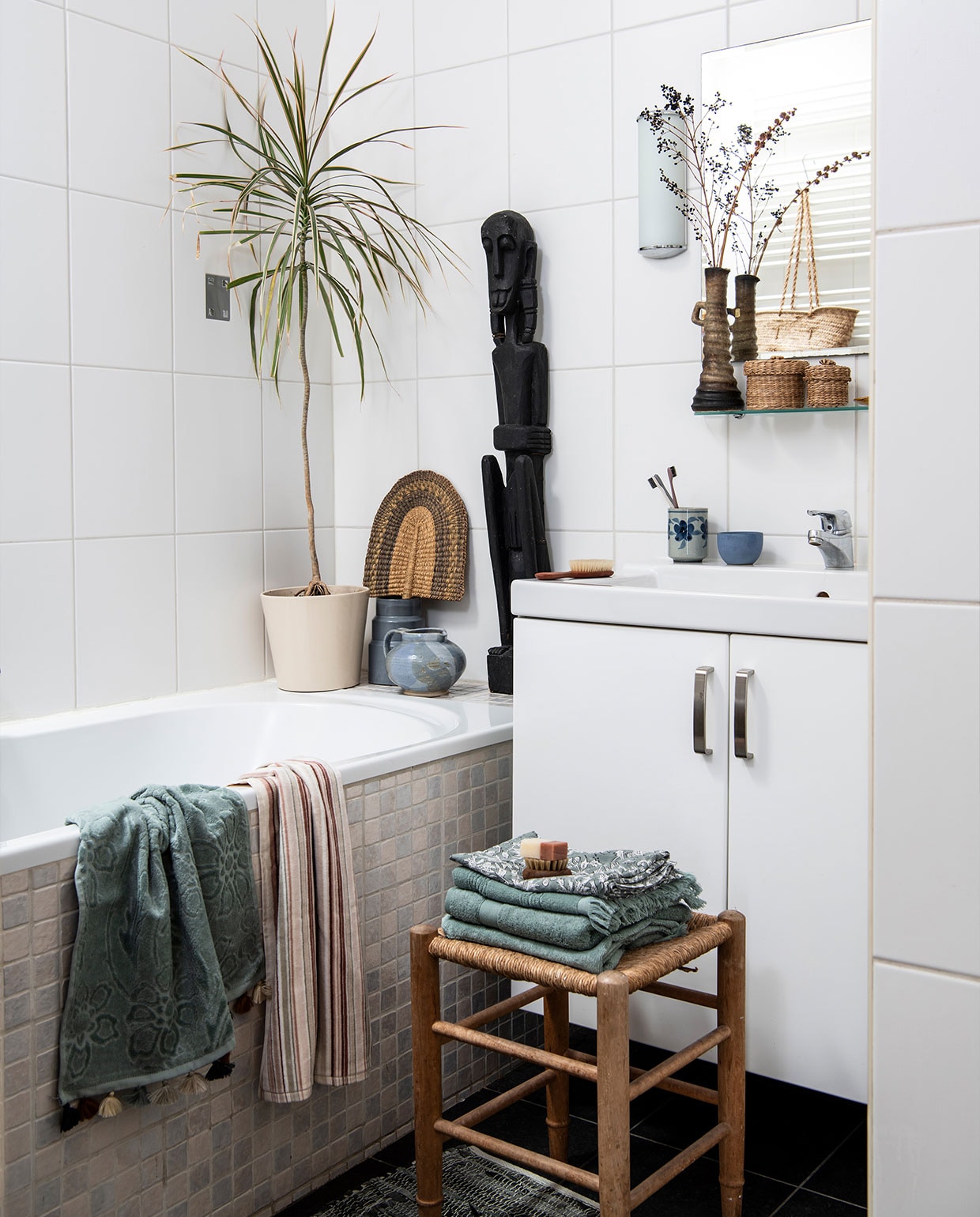 Vaas met droogbloemen, rieten manden, Afrikaanse kunst, kruk, tandenpoetsbeker tweedehands. Keramische pot D&amp;M Deco. Handdoeken Zara Home, badmat Søstrene Grene. Massageborstel Huishoudwinkel. Tanden- borstels Meraki. Plant Dracaena. Overig herkomst onbekend. vtwonen 02-2022 | productie Insidehomepage | styling Inge van Lieshout | fotografie Louis Lemaire