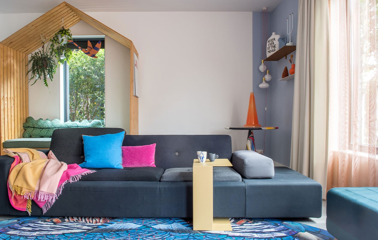 Speelhuis eigen ontwerp by Maykel, bladkussen Donna Wilson, zwaan Jantien Baas. Bank Polder Sofa en plaid Hella Jongerius voor Vitra, vloerkleed Moooi Carpets, blauw kussen Hay, paars kussen Nijhof, bijzettafel Gelderland Ori, kopje links Social Label, rechts Maarten Baas, poef Normann Copenhagen. Tafel in hoek Dirk Vander Kooij, kunstwerk Save me Glass Traffic Cone van Bas Kosters, wandplanken Muller van Severen, vaas Irenic Mould van Birgit Verwer via Cor Unum, karaf Muuto, kandelaar Chris Kabel voor Droog Design, duif Christien Meindertsma, oranje vaas Raawii, lampen Zangra. Vitrage van Kvadrat-stof, overgordijnen gemaakt door stoffeerder, kleur op muur onbekend. vtwonen 2-2022 | styling Kim de Groot | fotografie Anke Leunissen | tekst Mirjam Rosema-Verhulst