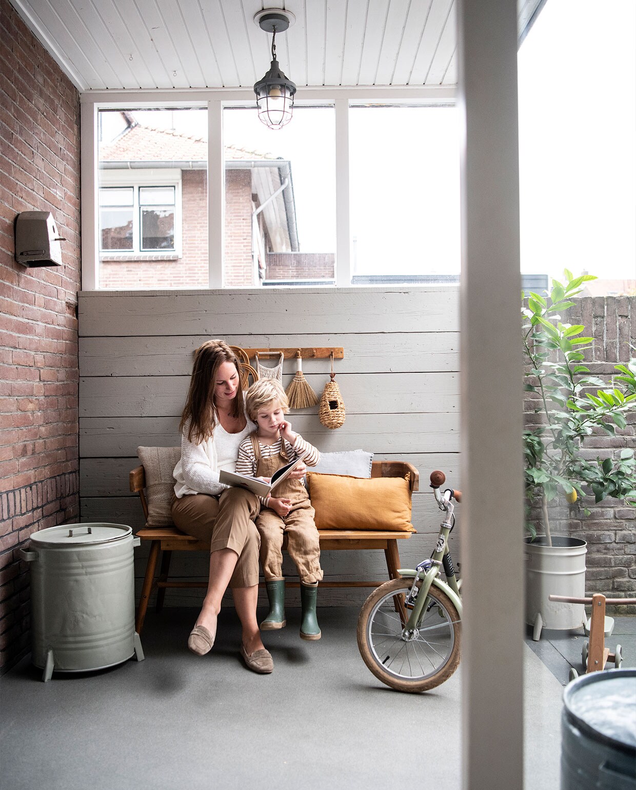 Bank Karwei. Bruin en grijs kussen Zara Home. Mosterdgeel kussen Sissy-Boy Homeland. Kapstok H&amp;M Home. Groen geverfde ronde bak Loods 5. Hanglamp V&amp;D. Kinderfiets Veloretti. vtwonen special DIY 3-2021 | productie Inside Homepage | styling Janneke Peters | fotografie Louis Lemaire