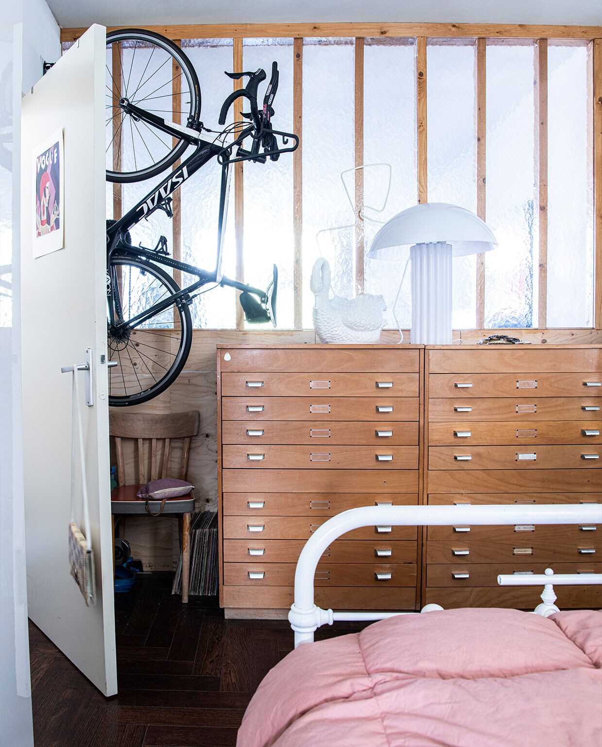 Poster op de deur souvenir uit Parijs. Handtas aan de deur dorisvintage.nl. Stoel Noppes. Archiefkast Gideon Italiaander. Witte zwaan en bed erfstuk. Witte lamp HKliving. Bedlinnen Kwantum. Fiets Isaac Cycle. vtwonen 2-2022 | Productie Insidehomepage | Styling Kim Timmerman | Fotografie Louis Lemaire | Tekst Inge van Lieshout | Tekstbewerking Merel van der Lande