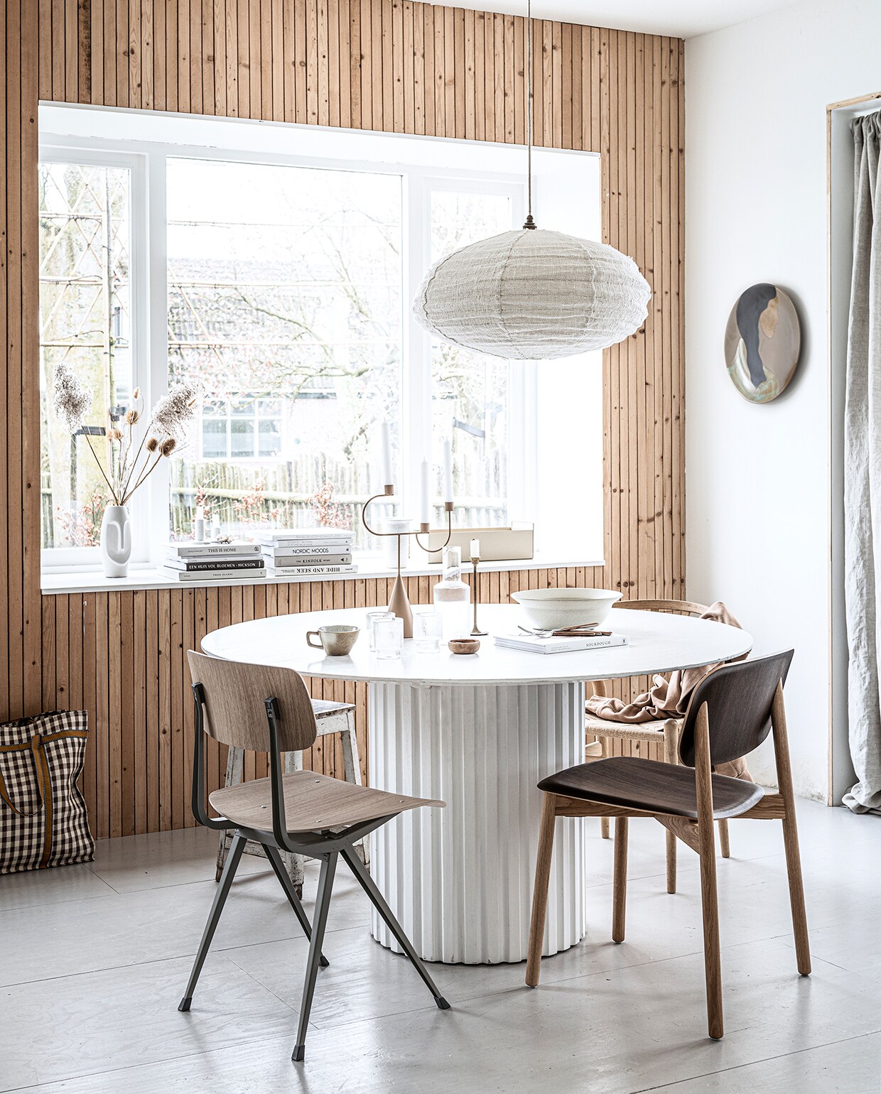 Eettafel Pillar van HKliving, 140×75 cm (Øxh), eetkamerstoel met stalen onderstel Result van Hay, geribbelde glazen van Ferm Living per 4, geribbelde karaf van Ferm Living, keramieken bord aan de wand Hessa van Ferm Living, beige kandelaar van Ferm Living, beige bak van Ferm Living (vtwonen.nl). Donker eikenhouten eetkamerstoel Hay Soft Edge, eikenhouten eetkamerstoel Wishbone CH24 (misterdesign.nl). Kookboek op tafel (hm.com). Stoffen hanglamp Kapok Tree in Natural/Beige (thebizzcollection.com). Linnen gordijn 140×300 cm, kopje, kom, houten bestek, shopper (zarahome.com). Overig privébezit. vtwonen 9-2021 DIY special 1  | productie &amp; styling kim van rossenberg | uitvoering Richard van Meerveld | fotografie Sjoerd Eickmans | assistentie Sanne van der Beek, Robin Folkerts