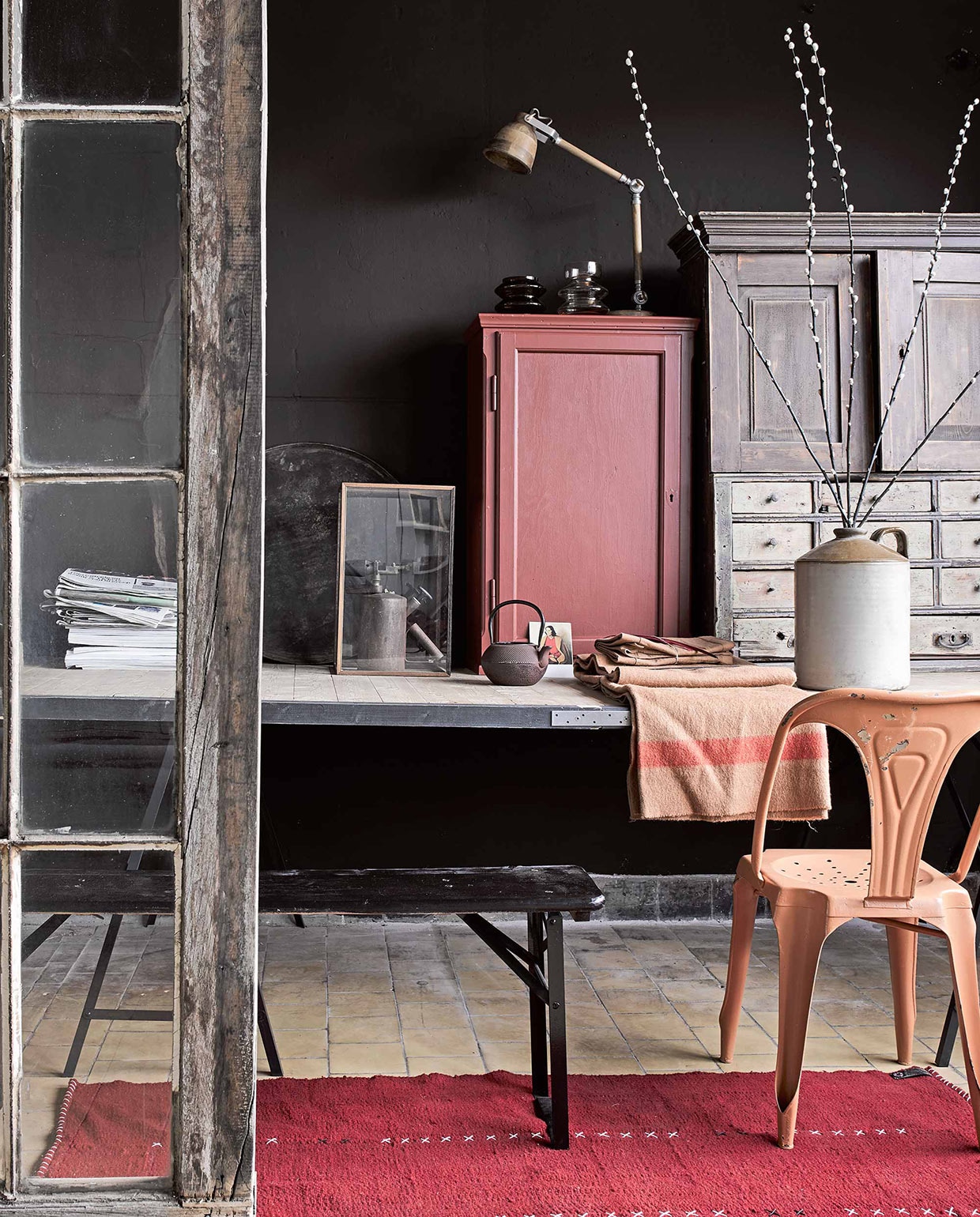 Op de muur krijtverf Jungle per liter € 22,- (Home made by). Wollen vloerkleed 90×180 cm € 299,- (Room 2a). Kast € 95,- (Combitex), geverfd in lakverf Beaujolais per liter € 38,50 (Home made by). Tafel € 450,-, stoel € 125,-, ladekastje € 395,-, oud apparaat € 35,-, aardappelzakstof op tafel (Combitex). Houten tafellamp € 205,-, theepot € 55,-, kruik met oor € 75,-, bank als onderdeel van een set van 2 banken € 275,-, alles van Madam Stoltz (Deens). Ansichtkaart € 0,95 (Art Unlimited). Vitrinekastje € 99,- (Loft). vtwonen 03-2017 | Fotografie Alexander van Berge | Styling Marianne Luning