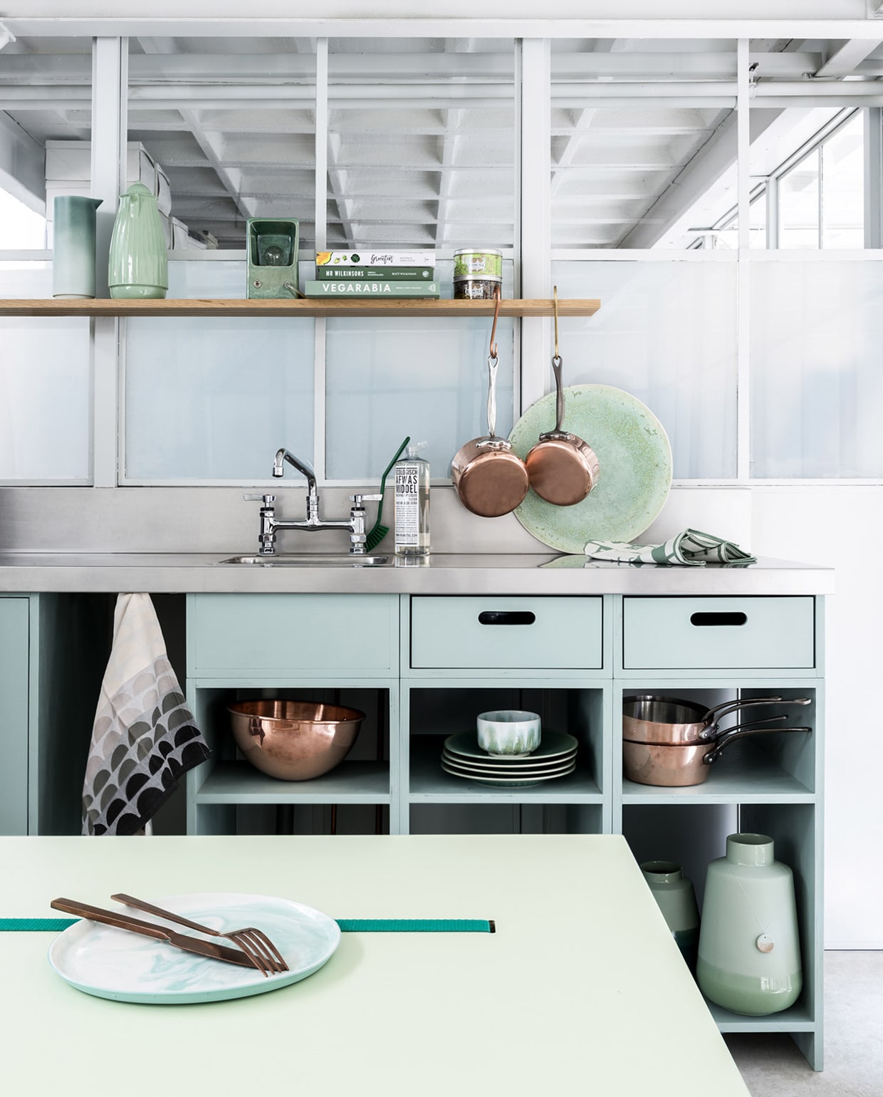 Keuken op maat gemaakt prijs op aanvraag (Sukha). Verfkleur keuken is Pigeon nr. 25 (Farrow &amp; Ball). Broodplank, kruk, kommen en bekers, grote schalen en schaal met leren lus, kleine borden , houten vaas, houten lepels en kookgerei (Sukha). Lampen (M.oss). Witte emaillen maatbekers klein en groot en pastelkleurige pannen (Riess). vtwonen 06-2018 | fotografie Stan Koolen | styling Marianne Luning