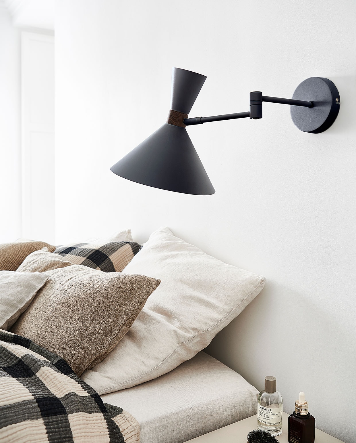 Matzwarte metalen wandlamp Hoodies, 25x25x50,5 cm (ook verkrijgbaar in mat zandgrijs) | M.m.v. hm.com (geblokt plaid en bijpassend kussen), zarahome.com (kussens). Overig privébezit. vtwonen 3-2022 | productie Tanja Saarberg | styling Kim van Rossenberg  | fotografie Sjoerd Eickmans