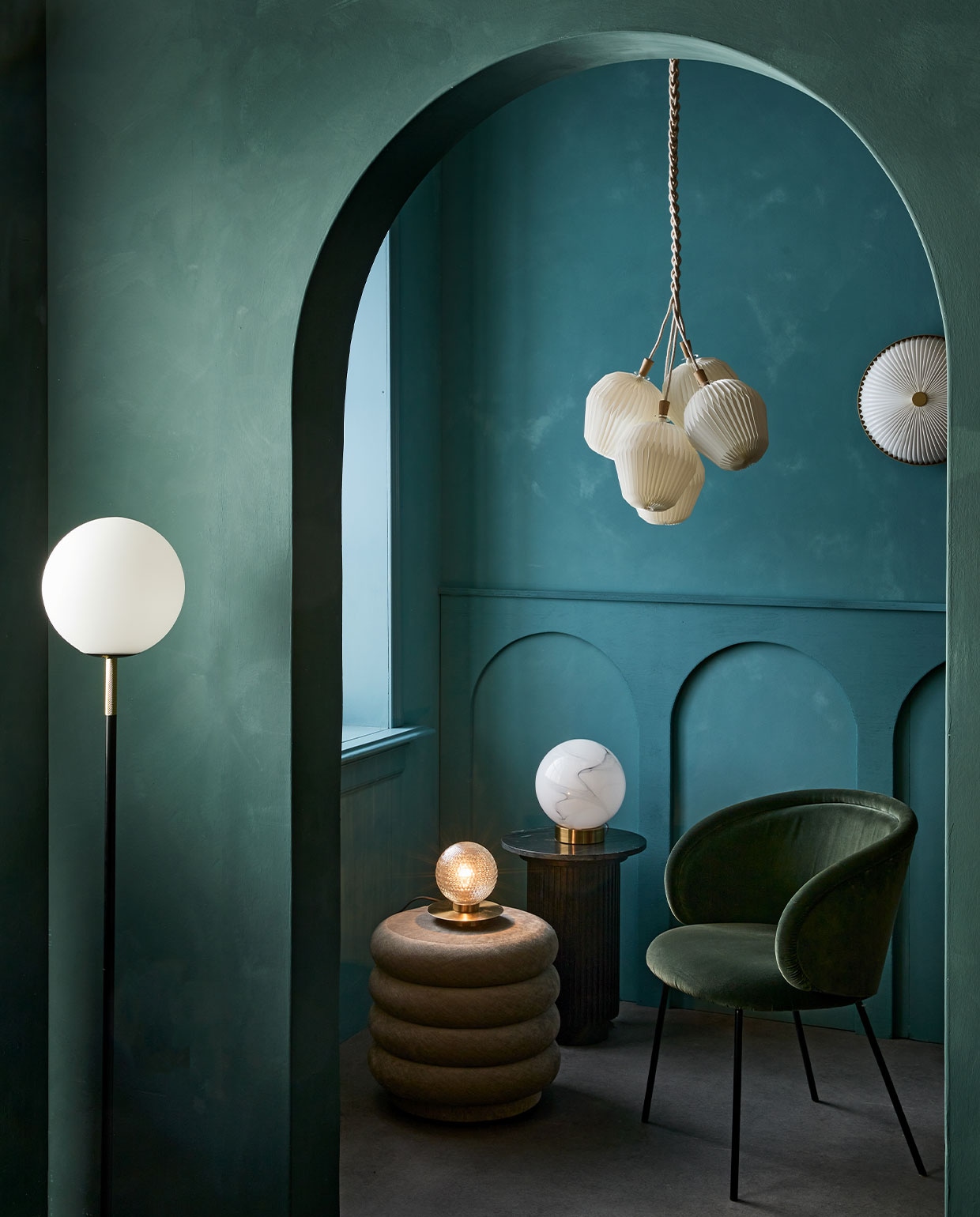 Kalkverf op de achterste muur 87 Petrol, op de muur met boog Staal/Steel 97, 2,5 liter € 126,- (lauthentique.nl). Vloerlamp Orion van Zuiver € 195,-(vtwonen.nl). Marmerlook tafellamp € 139,-, kleine gefacetteerde tafellamp met gouden voet € 98,-, zwarte marmeren bijzettafel € 419,89 (nordal.eu). Poef Faded Velvet van Ferm Living € 695,-, eetkamerstoel Ona vanaf € 968,- (edha-interieur.nl). Wandlamp, 35 cm (Ø) € 628,-, hanglamp The Bouquet Chandelier Five Shades € 902,- (leklint.dk).