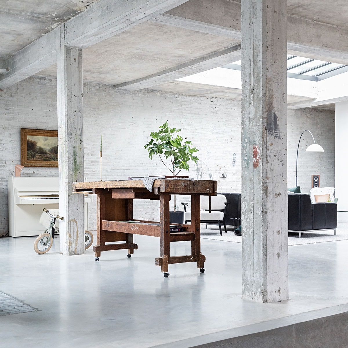 Vloer gevlinderd beton. Hardstenen waaltjes Spotted Bluestone. Werkbank erfstuk meubelfabriek. Kinderfiets Trybike. Witte fauteuil Ode Lounge Chair van Studio Henk. styling Ilona Jongepier | fotografie Dana van Leeuwen | visagie Djolien de Kreij | tekst Merel van der Lande