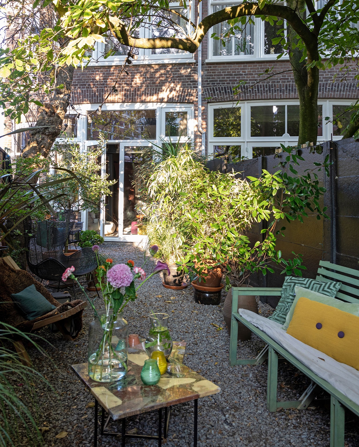 Groene bank Weltevree. Groen vierkant kussen en lichtgroen kussen H&amp;M Home. Geel kussen Hay. Dekbedovertrek By Mölle. Bijzettafel en waterkaraf vintage. Buitenkaarsen Bolsius. Vaas vtwonen. Stoel HKliving. Schapenvacht Vacht van Vilt. Kussen laten maken met stof van Dedar. vtwonen TUIN special 3 | Styling Theo-Bert Pot, Jelle Van de Schoor | fotografie Theo-Bert Pot | tekst Cathelijne van Wingerden