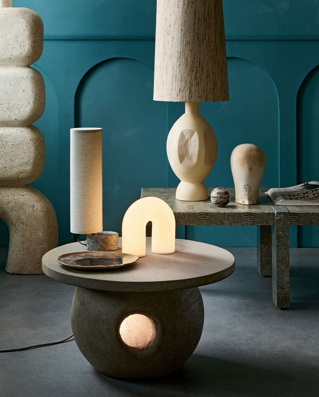 Kalkverf op de muur 87 Petrol, 2,5 liter € 126,-(lauthentique.nl). Tafel met licht € 800,-, links: voet van sculpturale vloerlamp van microcement € 1150,-(lanena-home.com). Witte tafellamp Vuelta van Ferm Living € 199,- (vtwonen.nl). Tafellamp met marmeren voet Unbound van Gubi vanaf € 549,- (gubi.com). Keramieken lampvoet Boho € 179,-, kap € 109,95 (hkliving.nl). Object hoofd, prijs op aanvraag (vandijkenko.nl). Overig privébezit. vtwonen 1-2022 | styling Cleo Scheulderman | fotografie Jeroen van der Spek | decorbouw Milo Kol